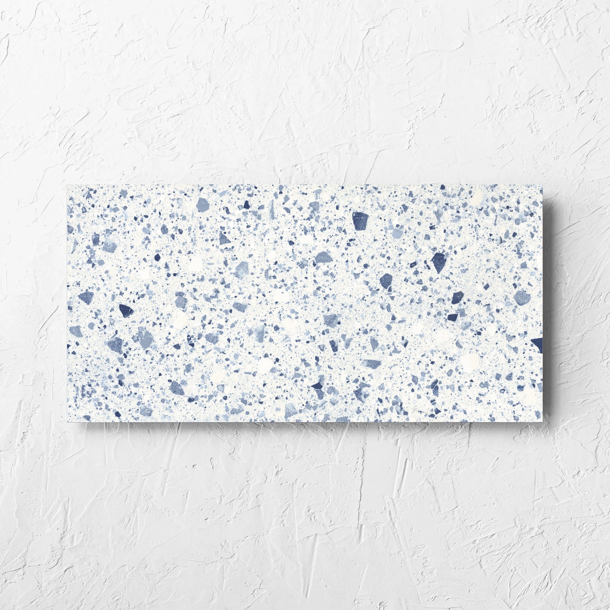 Venice Blue 300x600mm Matt Terrazzo Tile laid flat on a white rendered wall, showing the blue matt surface