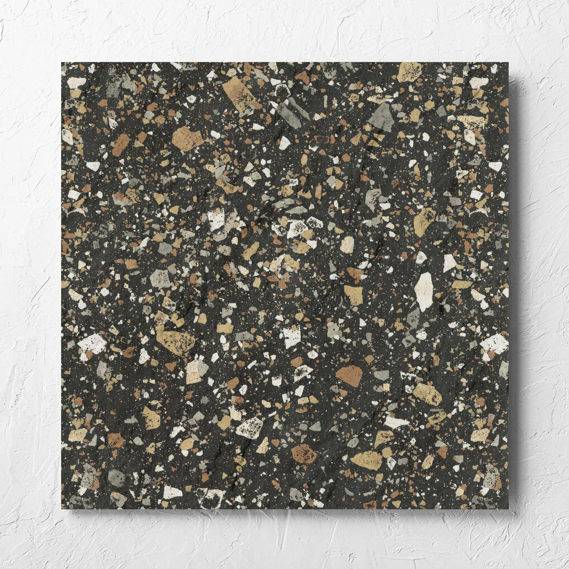 Venice Earth 600x600mm Matt Terrazzo External Tile laid flat on a white rendered wall, showing the earth matt surface