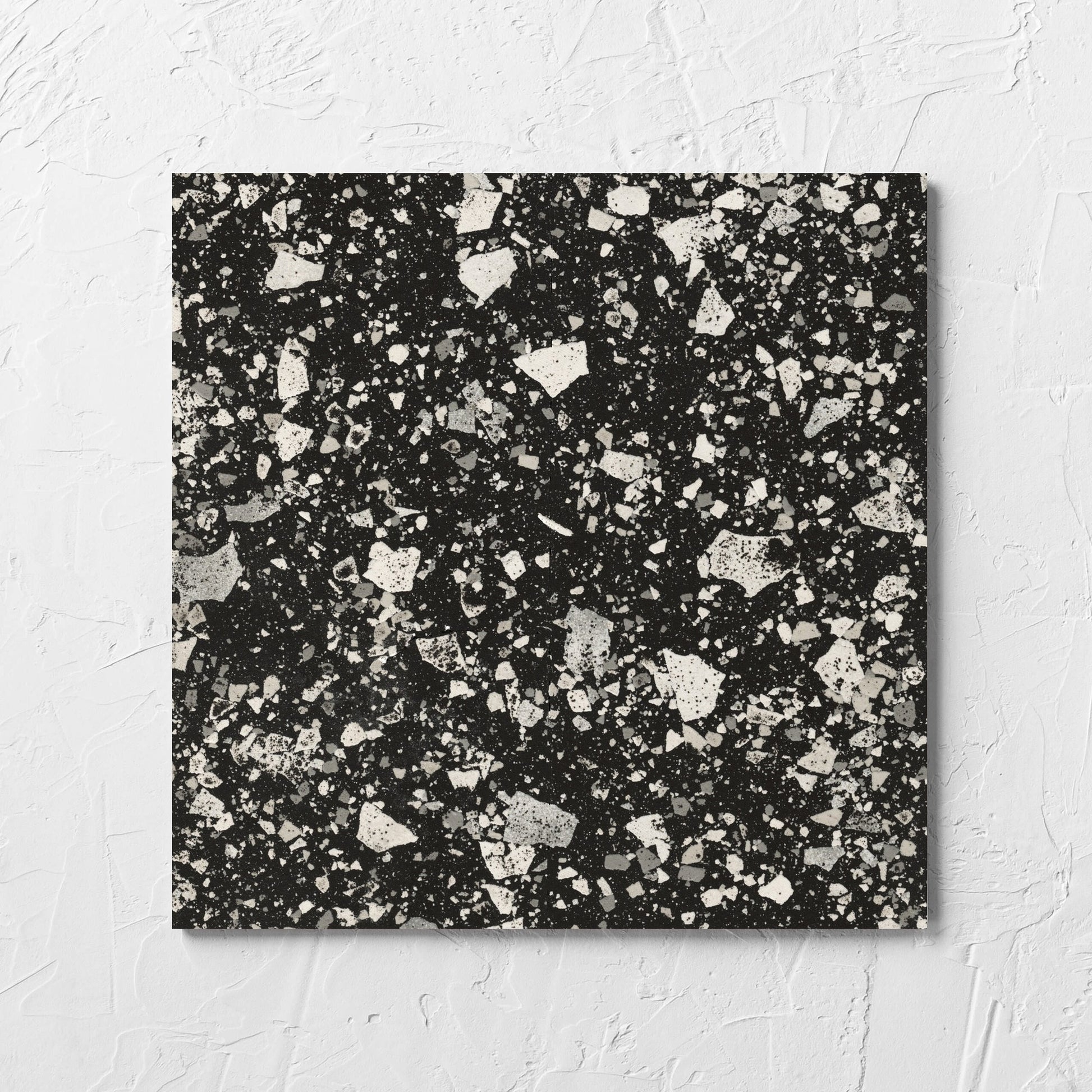 Venice Graphite 300x300mm Matt Terrazzo Tile laid flat on a white rendered wall, showing the graphite matt surface
