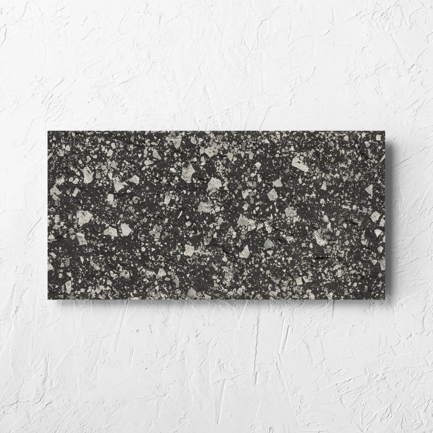 Venice Graphite 300x600mm Matt Terrazzo External Tile laid flat on a white rendered wall, showing the graphite matt surface