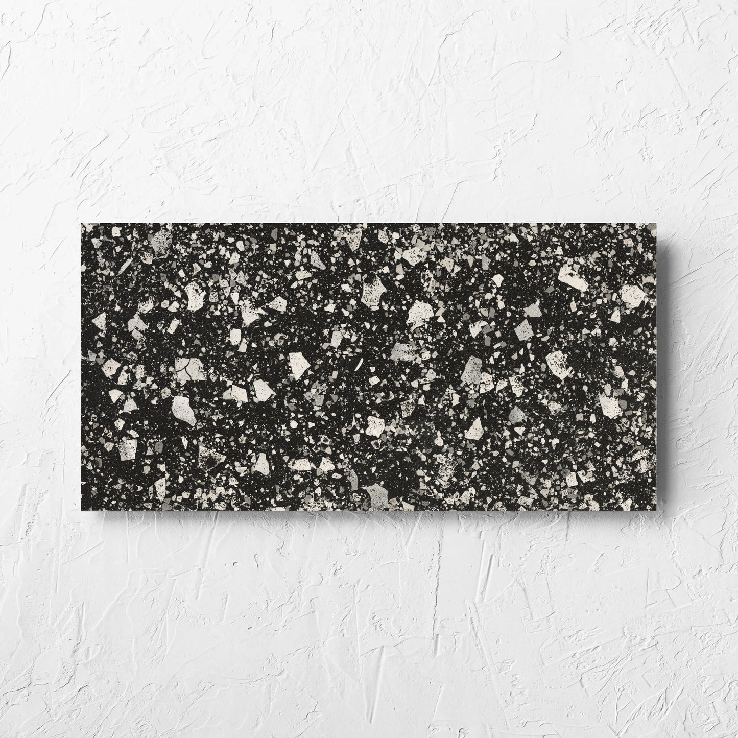 Venice Graphite 300x600mm Matt Terrazzo Tile laid flat on a white rendered wall, showing the graphite matt surface
