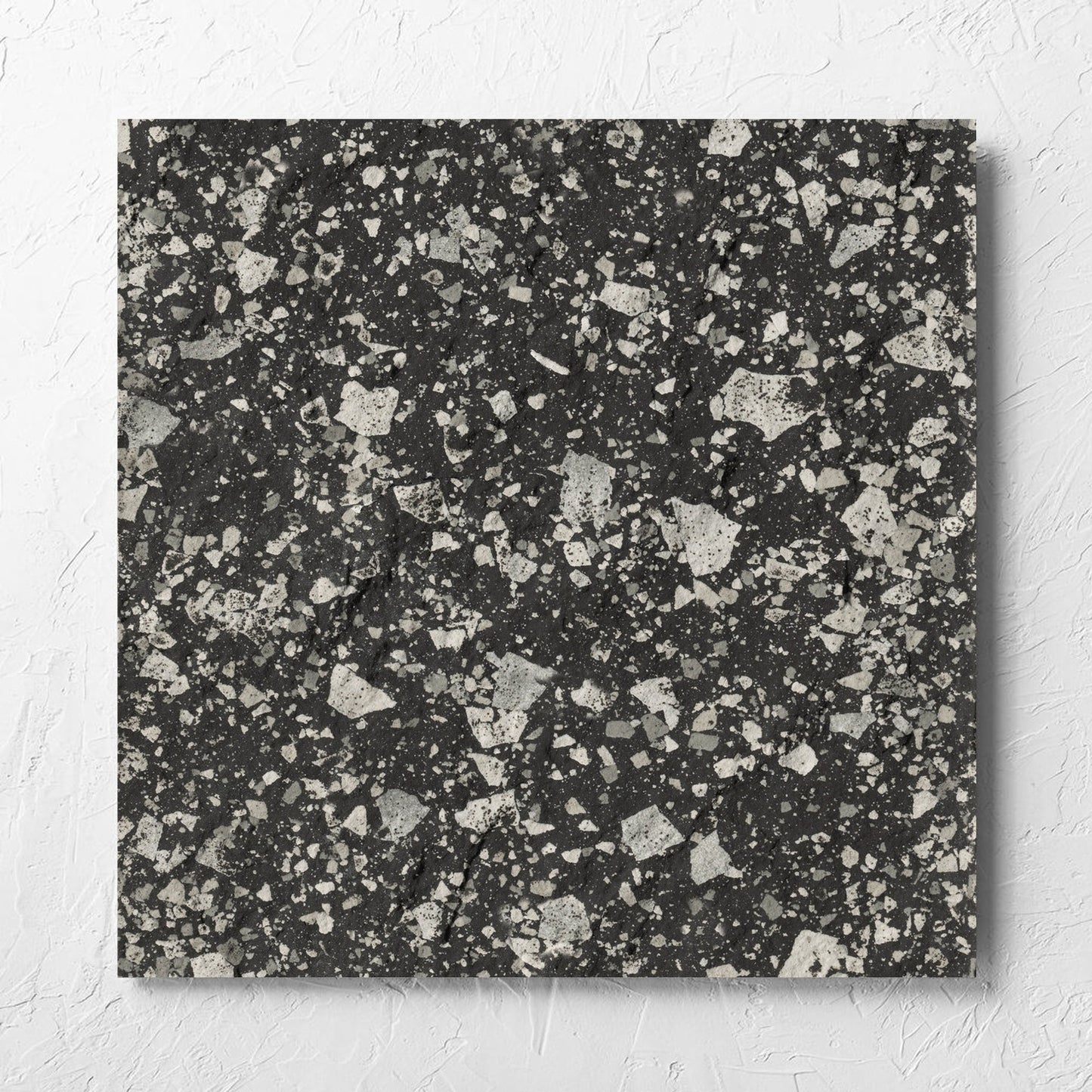 Venice Graphite 600x600mm Matt Terrazzo External Tile laid flat on a white rendered wall, showing the graphite matt surface