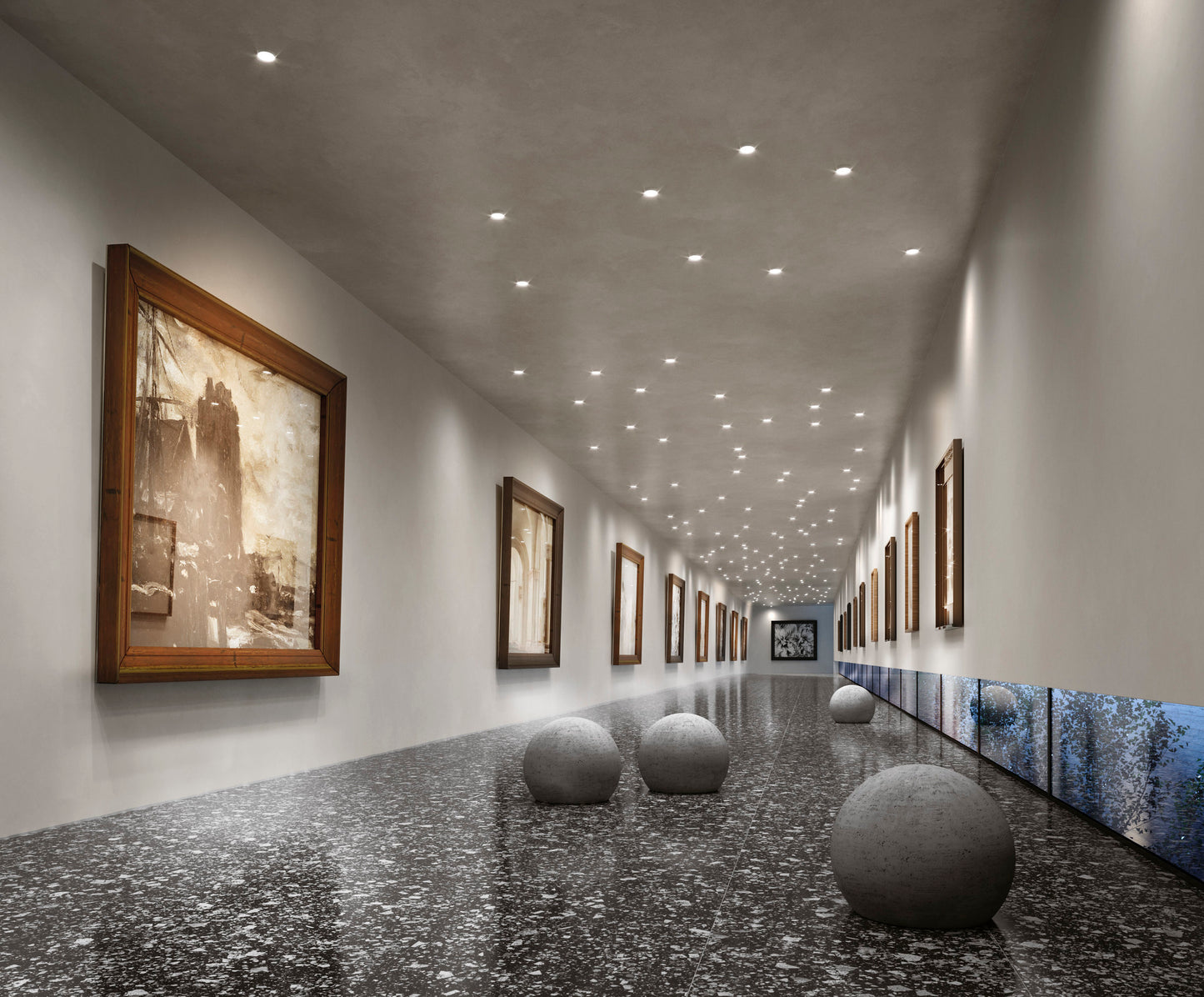 Venice Graphite 600x600mm Matt Terrazzo Tile installed in a contemporary art gallery corridor featuring stone sphere sculptures and recessed ceiling lights.