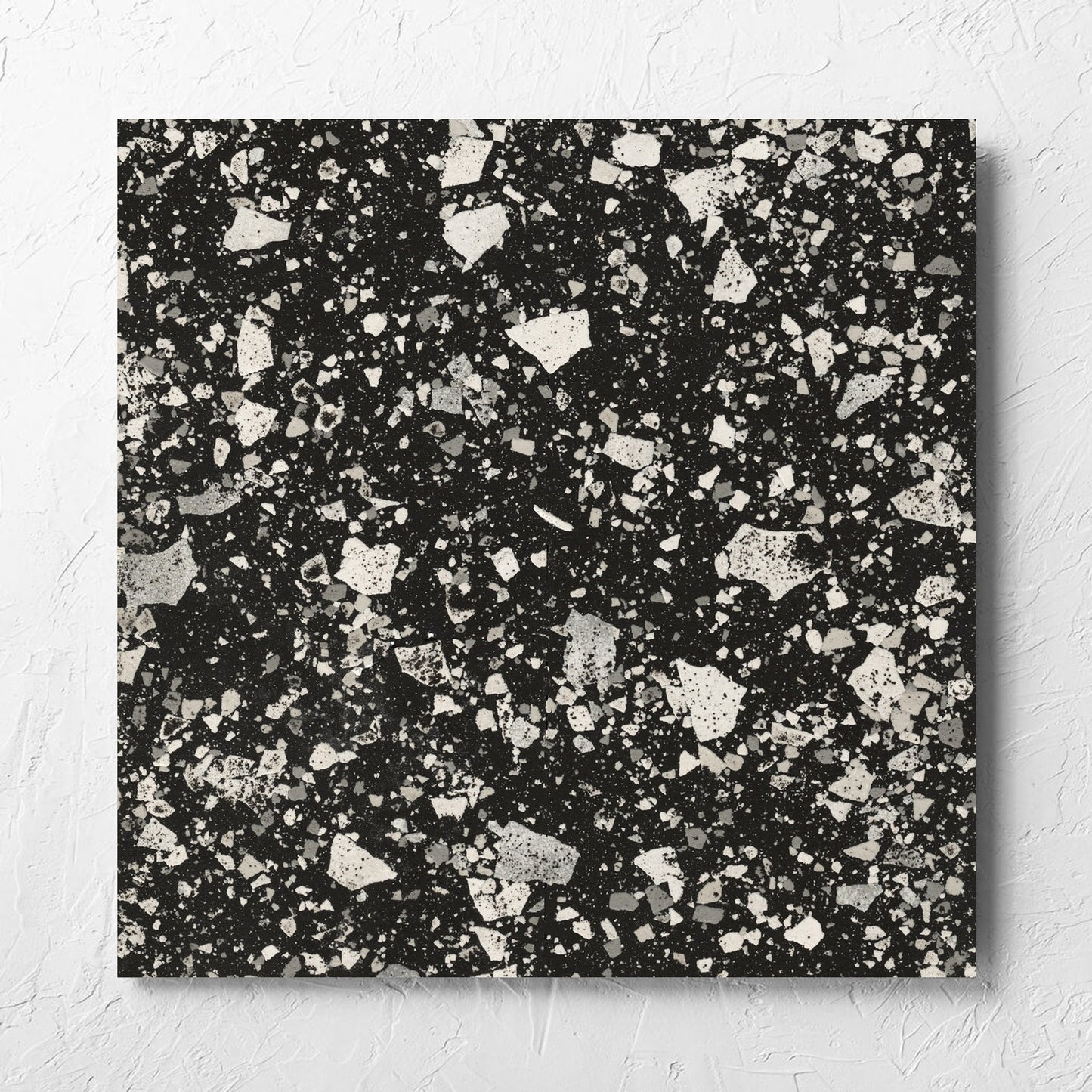 Venice Graphite 600x600mm Matt Terrazzo Tile laid flat on a white rendered wall, showing the graphite matt surface