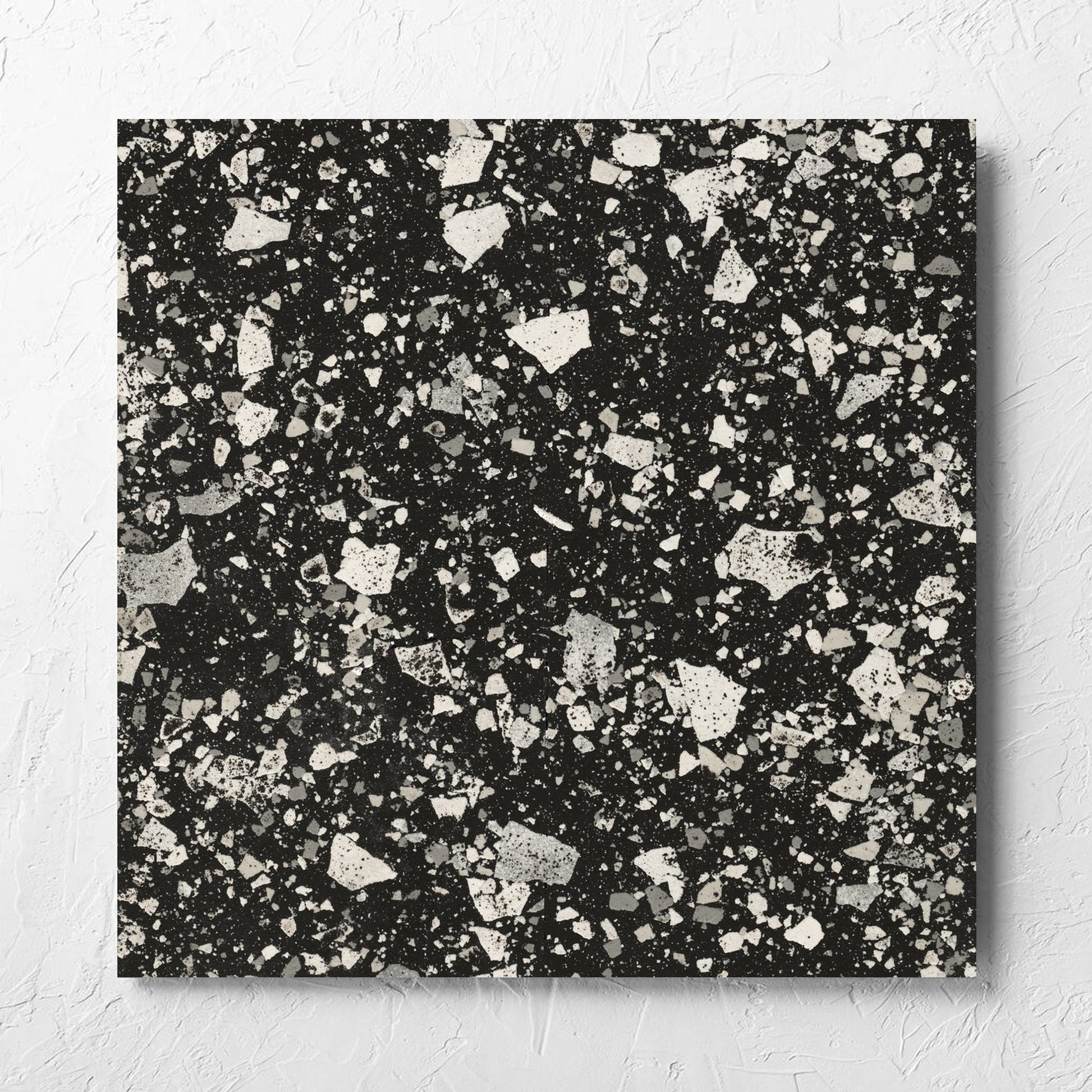 Venice Graphite 600x600mm Matt Terrazzo Tile laid flat on a white rendered wall, showing the graphite matt surface