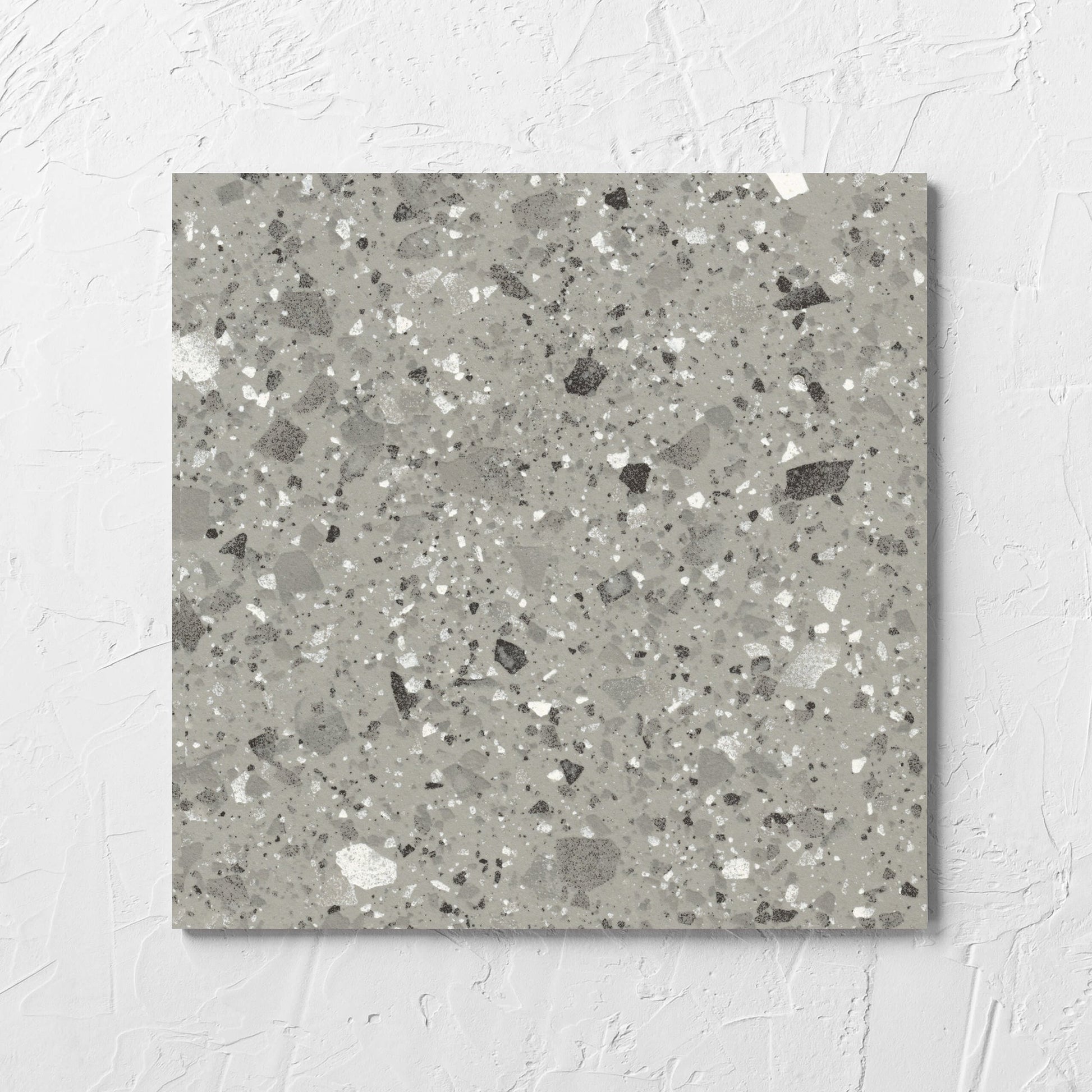 Venice Grey 300x300mm Matt Terrazzo Tile laid flat on a white rendered wall, showing the grey matt surface