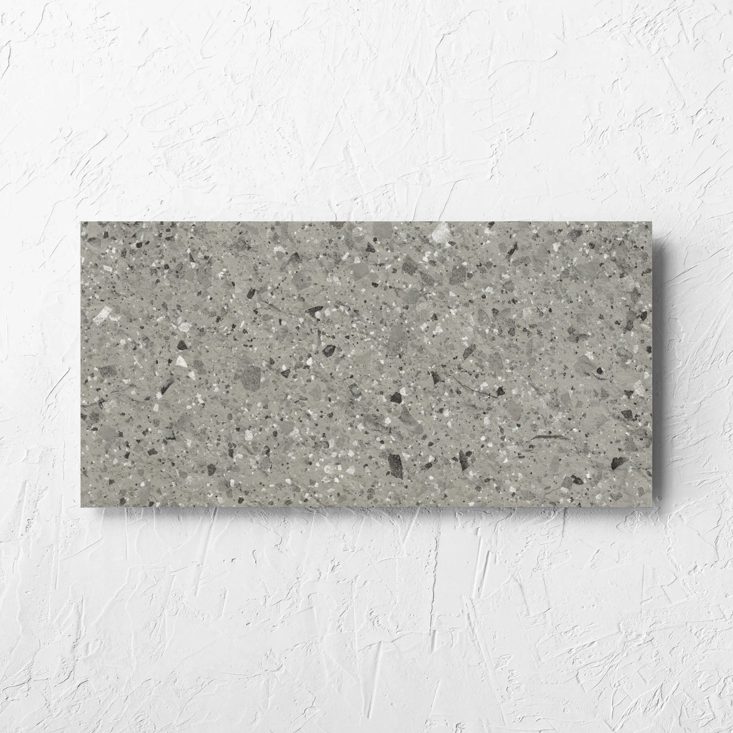Venice Grey 300x600mm Matt Terrazzo External Tile laid flat on a white rendered wall, showing the grey matt surface