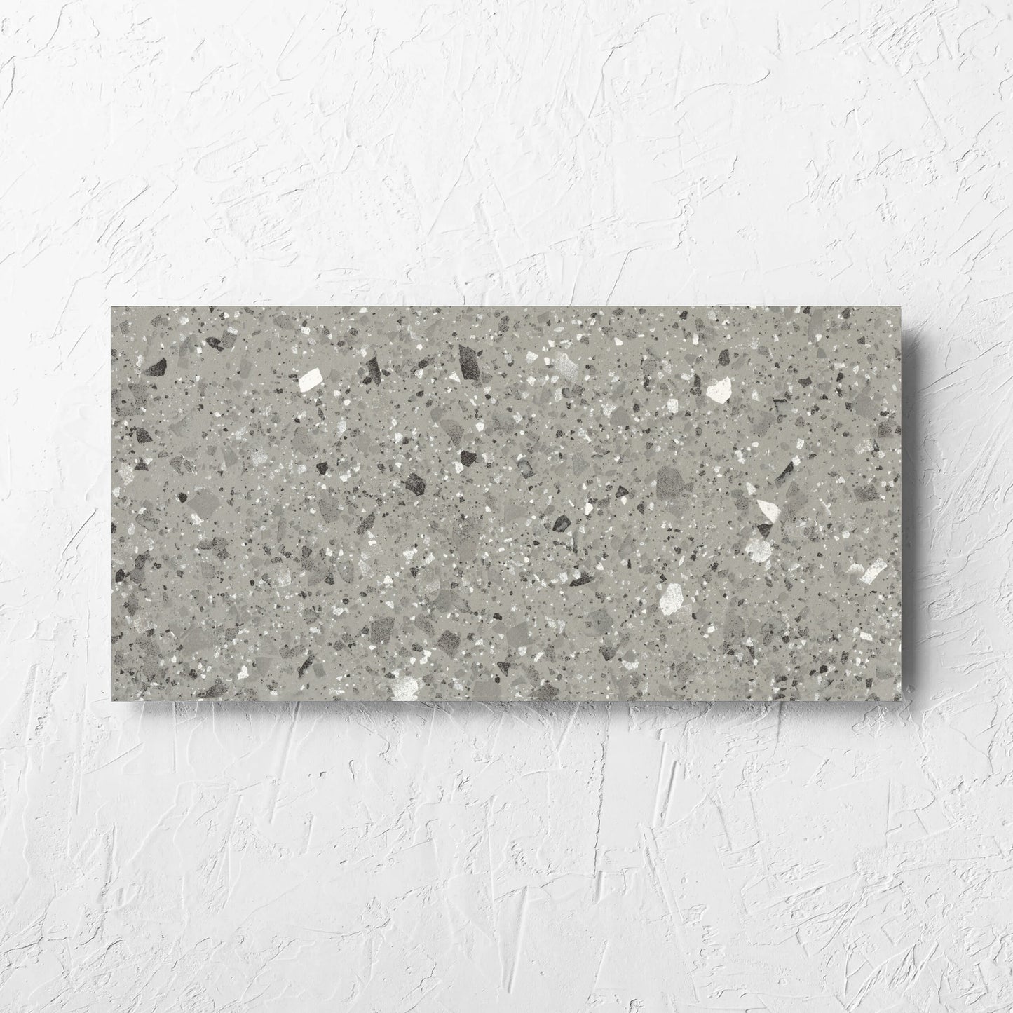 Venice Grey 300x600mm Matt Terrazzo Tile laid flat on a white rendered wall, showing the grey matt surface