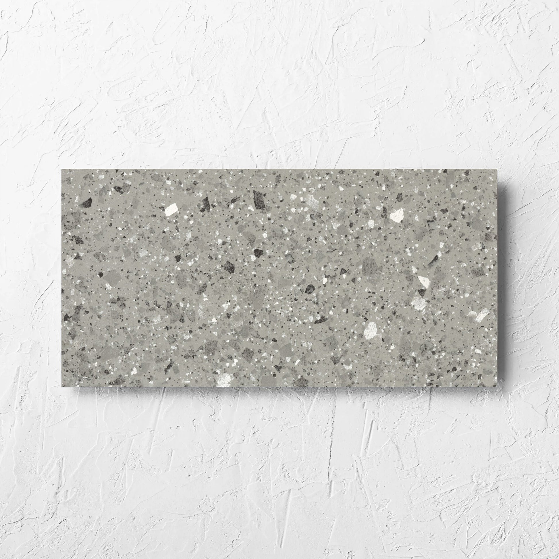 Venice Grey 300x600mm Matt Terrazzo Tile laid flat on a white rendered wall, showing the grey matt surface