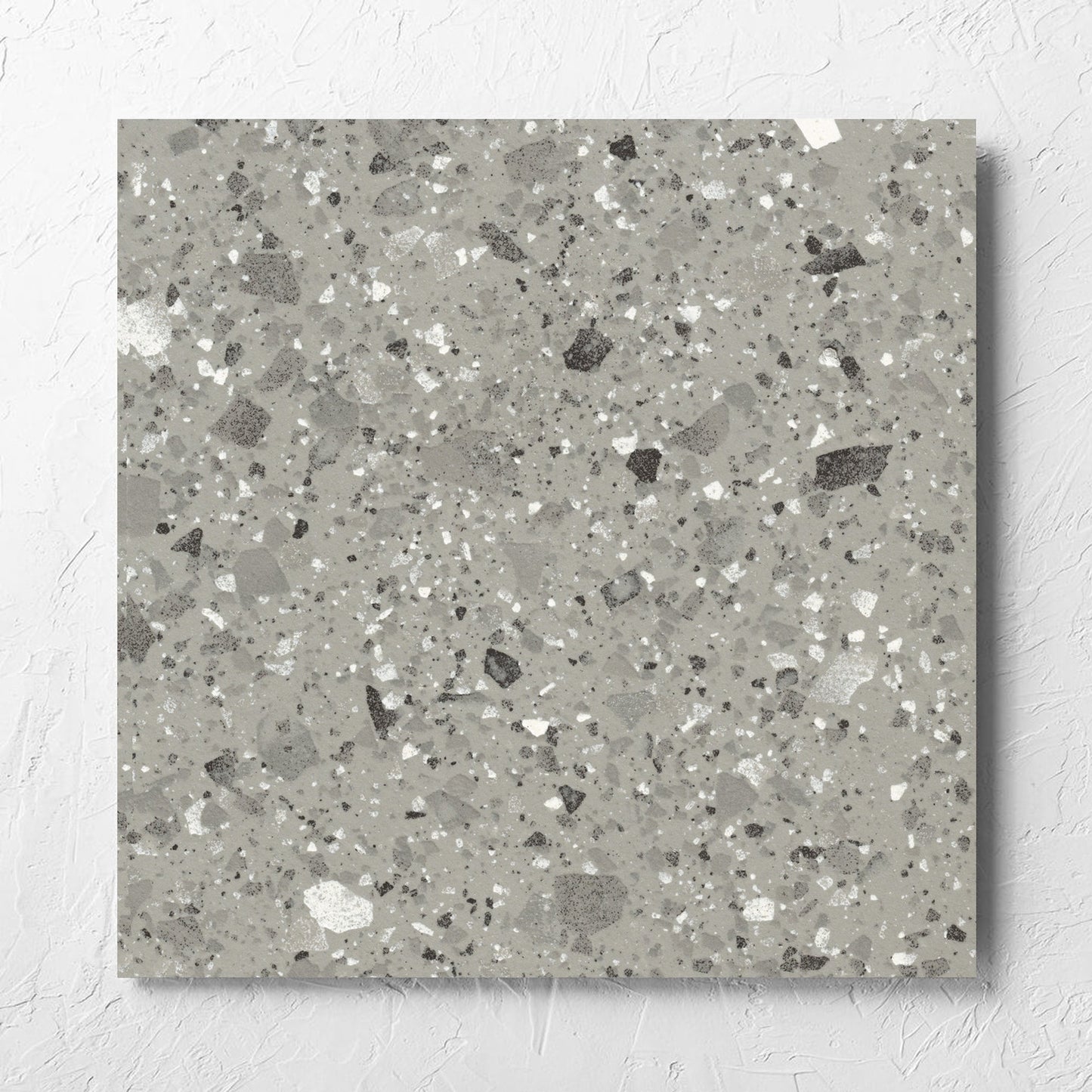 Venice Grey 600x600mm Matt Terrazzo Tile laid flat on a white rendered wall, showing the grey matt surface