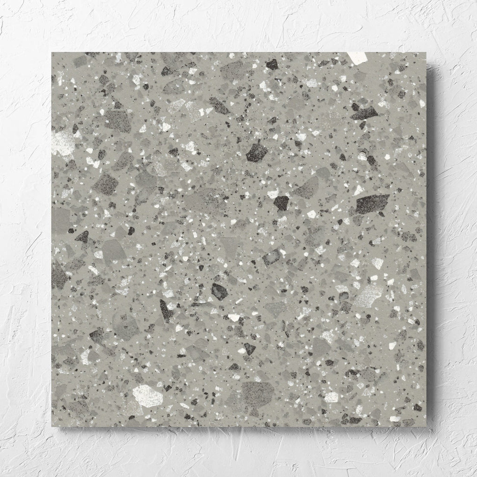 Venice Grey 600x600mm Matt Terrazzo Tile laid flat on a white rendered wall, showing the grey matt surface