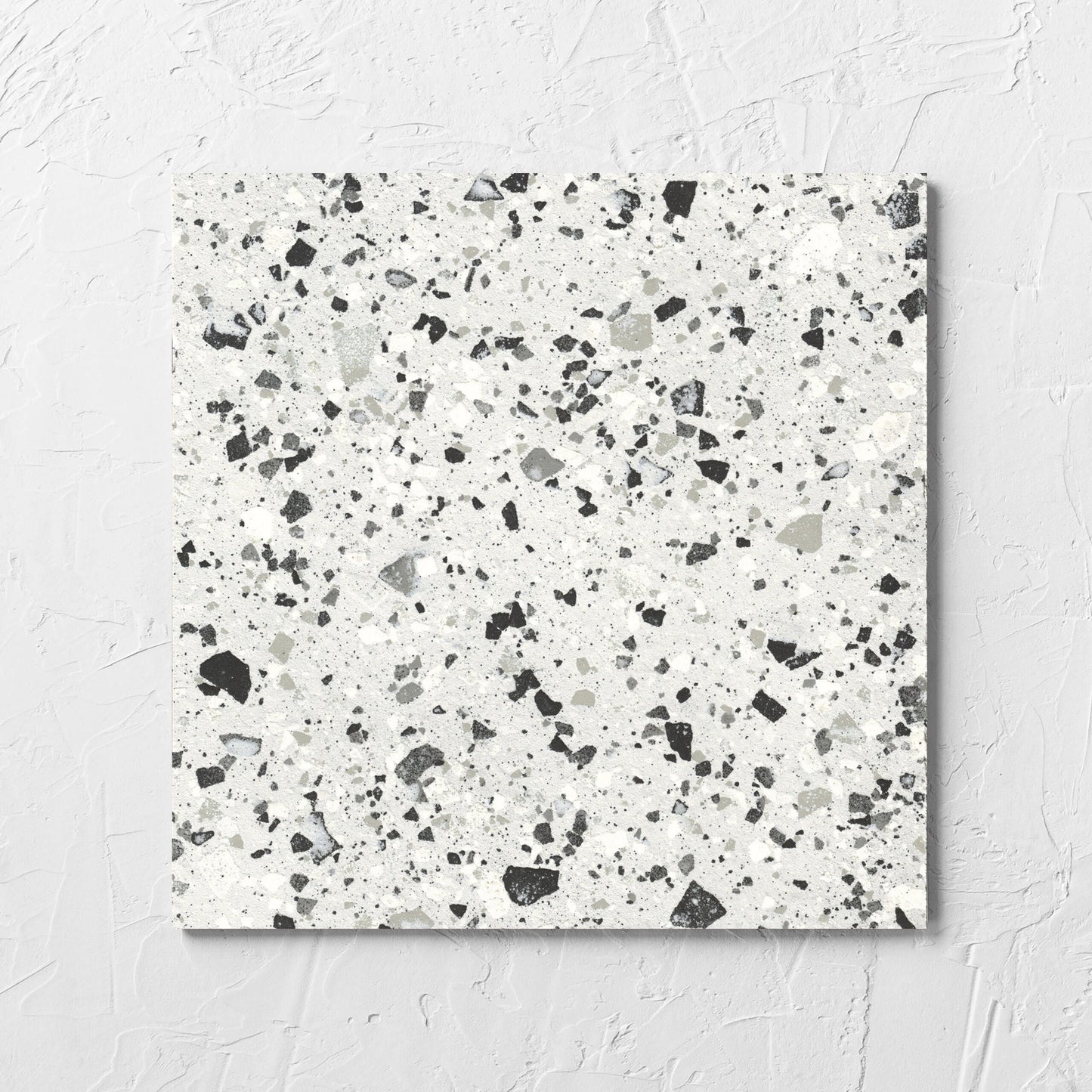 Venice Silver 300x300mm Matt Terrazzo Tile laid flat on a white rendered wall, showing the silver matt surface