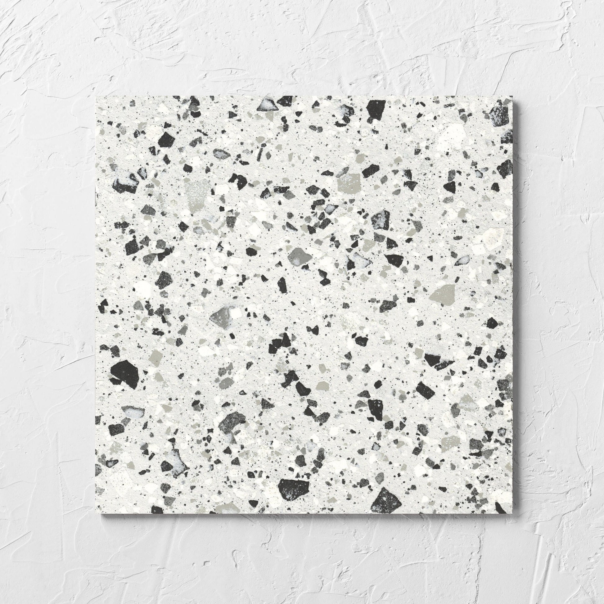 Venice Silver 300x300mm Matt Terrazzo Tile laid flat on a white rendered wall, showing the silver matt surface
