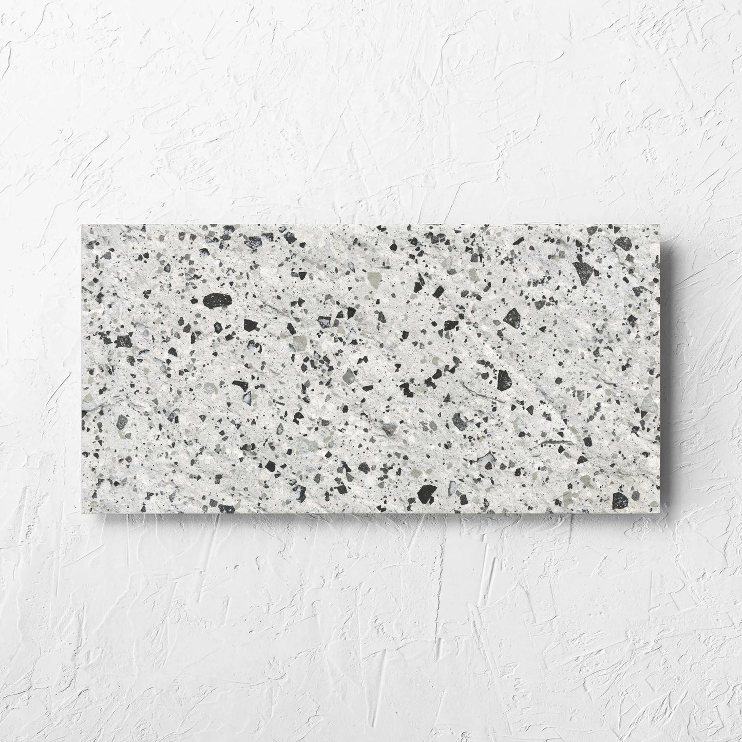 Venice Silver 300x600mm Matt Terrazzo External Tile laid flat on a white rendered wall, showing the silver matt surface