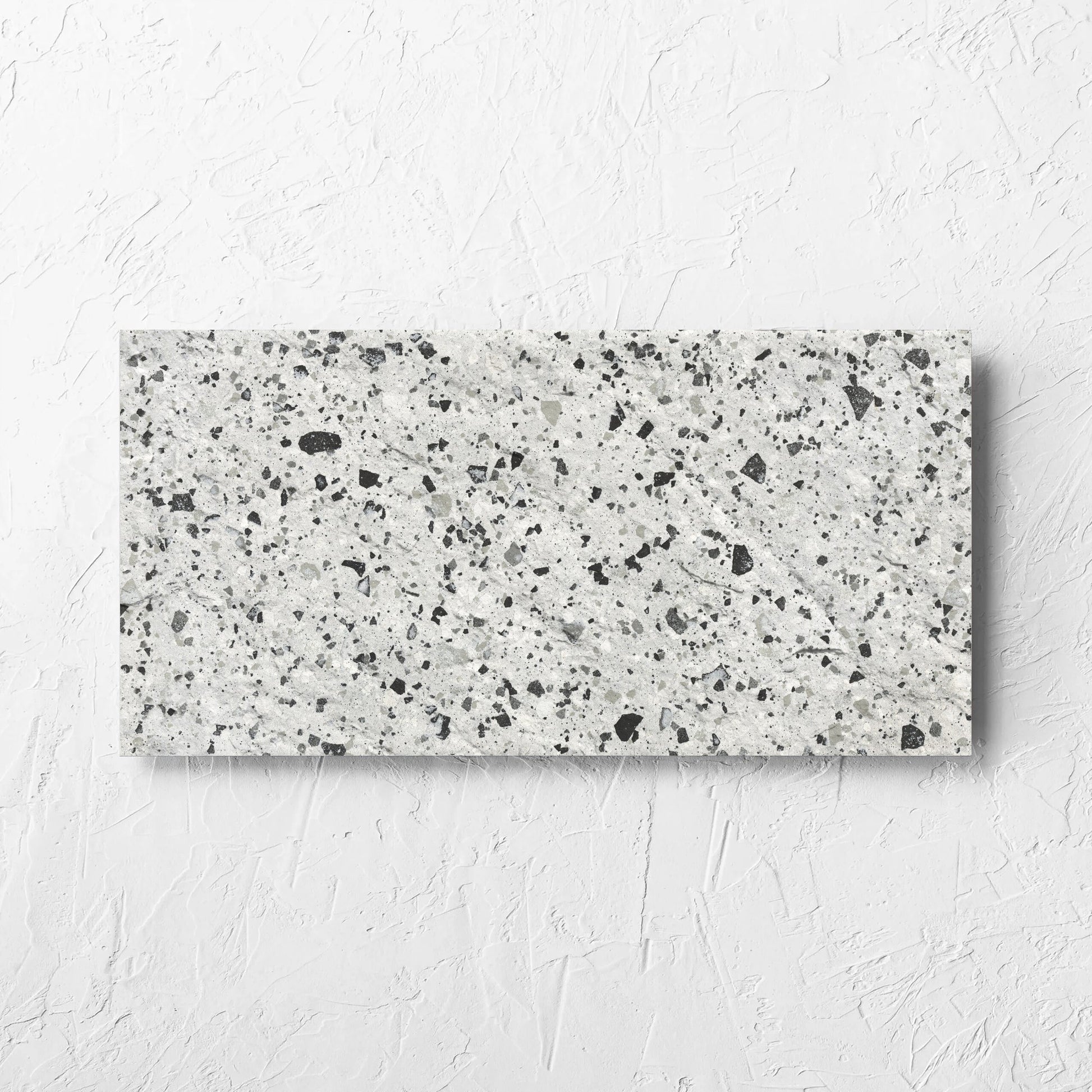 Venice Silver 300x600mm Matt Terrazzo External Tile laid flat on a white rendered wall, showing the silver matt surface