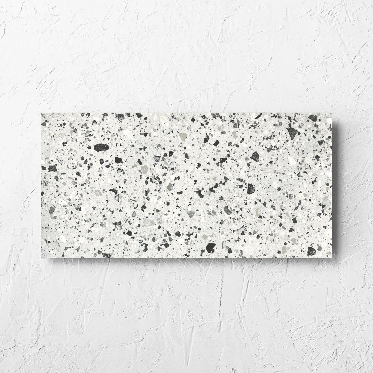 Venice Silver 300x600mm Matt Terrazzo Tile laid flat on a white rendered wall, showing the silver matt surface