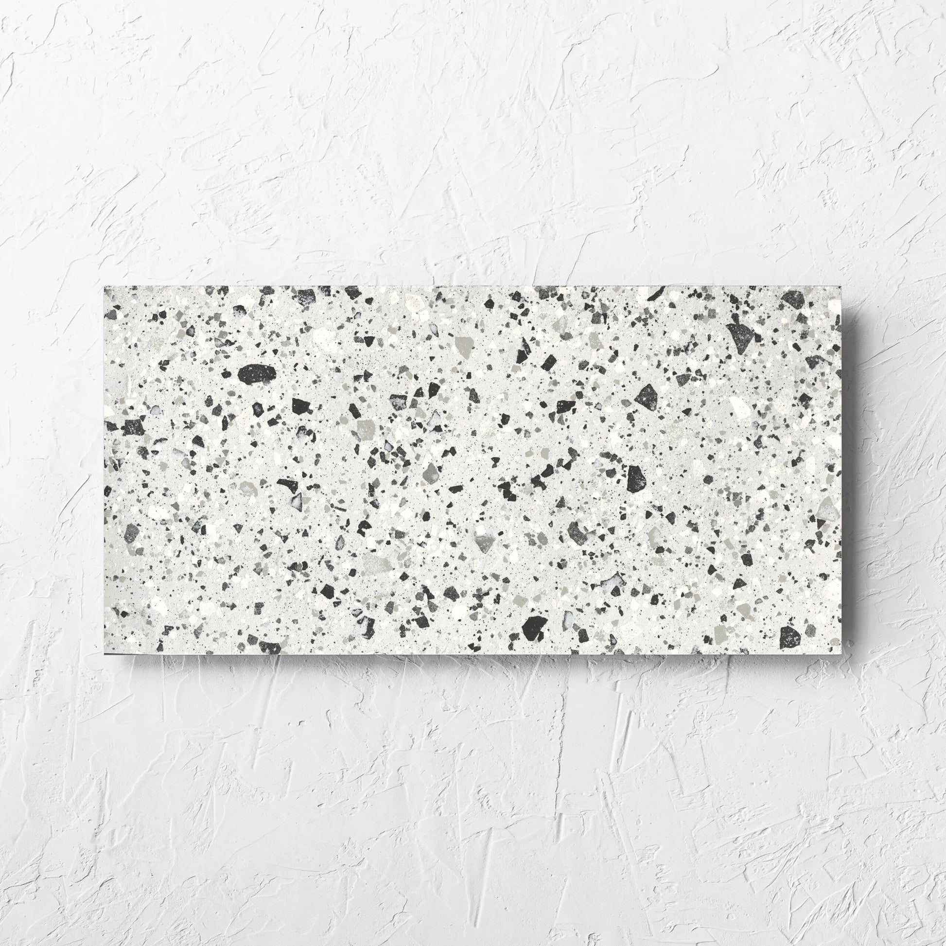Venice Silver 300x600mm Matt Terrazzo Tile laid flat on a white rendered wall, showing the silver matt surface