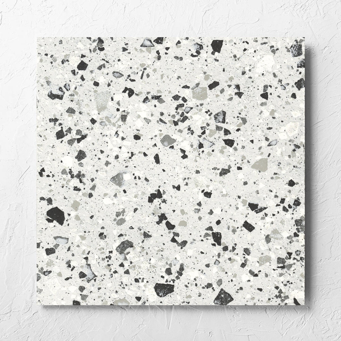 Venice Silver 600x600mm Matt Terrazzo Tile laid flat on a white rendered wall, showing the silver matt surface