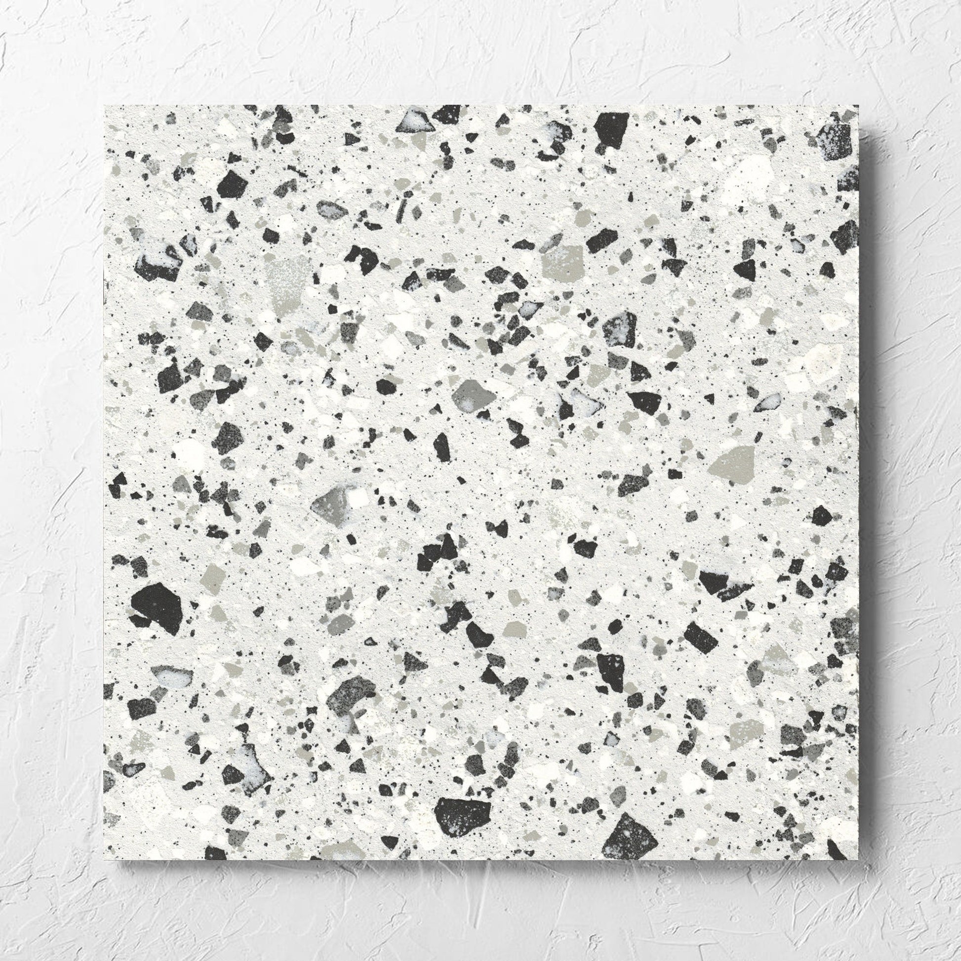 Venice Silver 600x600mm Matt Terrazzo Tile laid flat on a white rendered wall, showing the silver matt surface