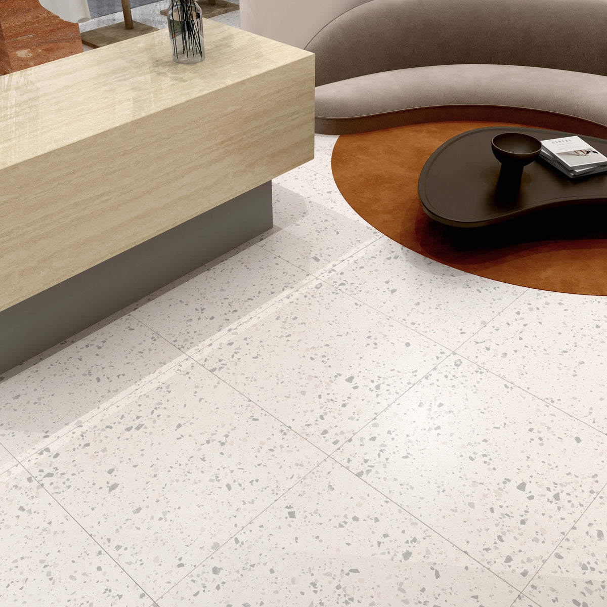 Venice Villa Zinc Matt Terrazzo 300x300mm tiles installed as a white speckled living room floor alongside a curved sofa and round rust-coloured rug.