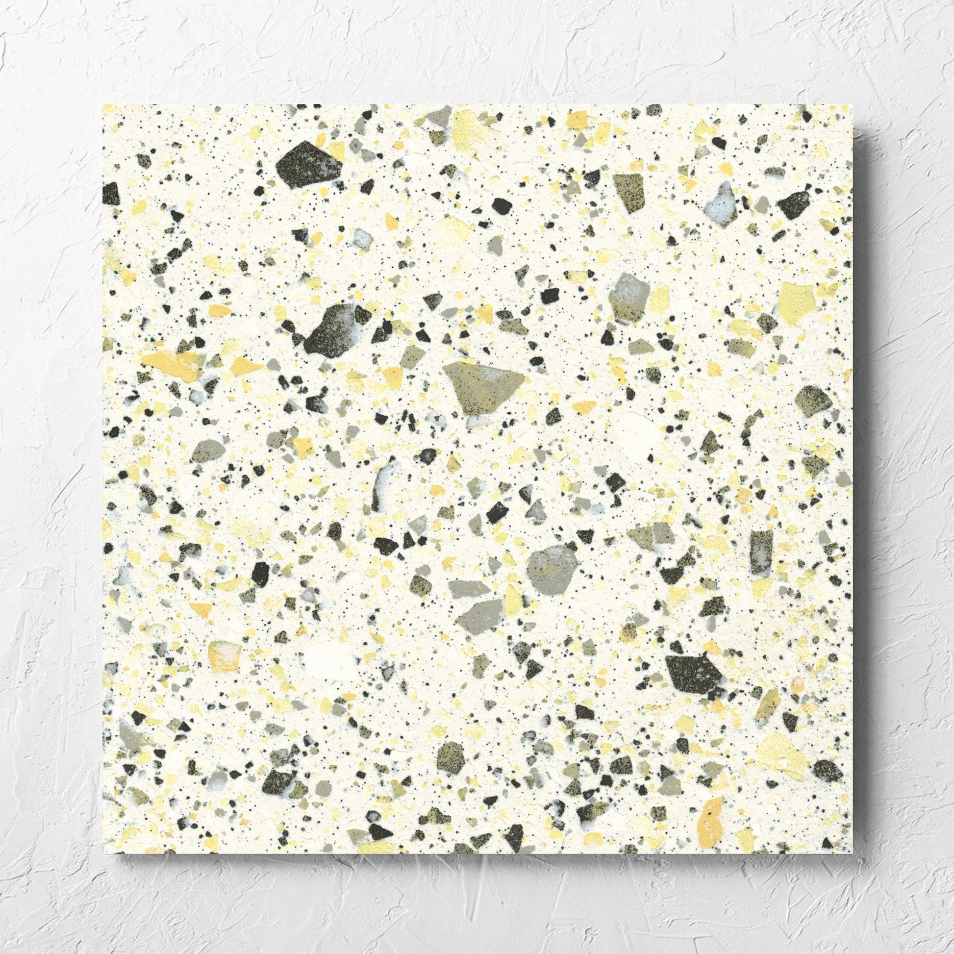 Venice Yellow 600x600mm Matt Terrazzo Tile laid flat on a white rendered wall, showing the yellow matt surface