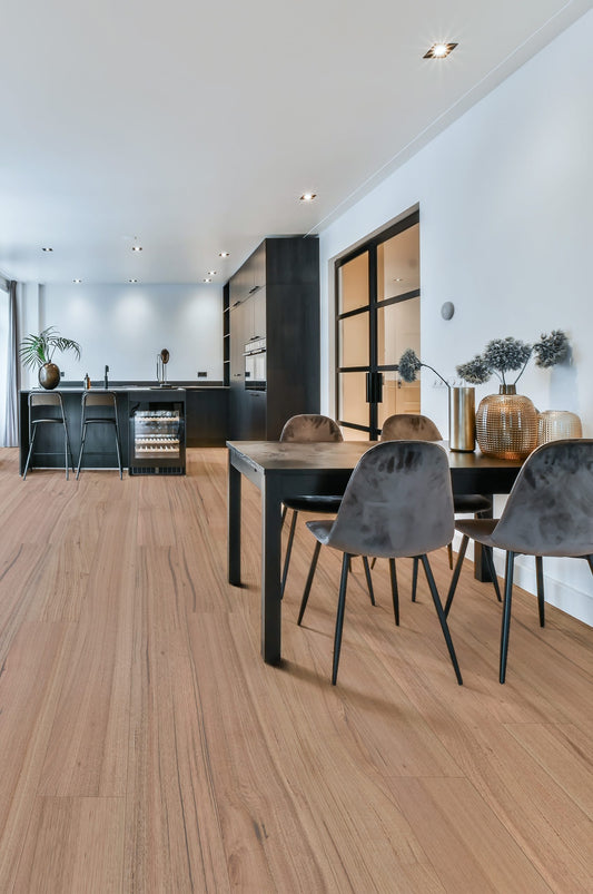 Victoria Ash Engineered Australian Classic Flooring 14/3mm installed in an open-plan dining and kitchen space with grey velvet chairs and black cabinetry.
