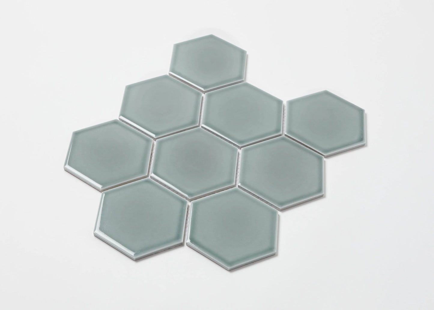 Pack shot of Water Green Gloss Porcelain Glazed Hexagon 95x110mm tiles arranged in a honeycomb cluster, showing smooth glossy finish and soft sage-green colour.