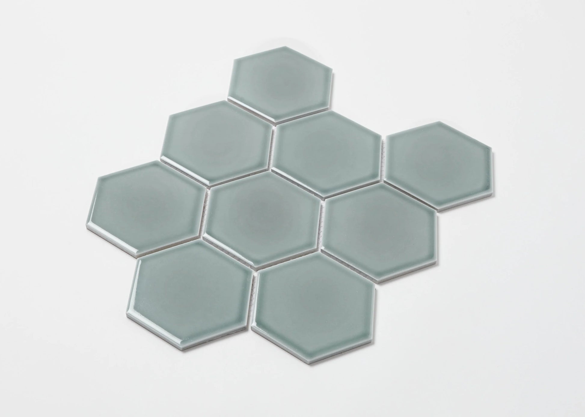 Pack shot of Water Green Gloss Porcelain Glazed Hexagon 95x110mm tiles arranged in a honeycomb cluster, showing smooth glossy finish and soft sage-green colour.