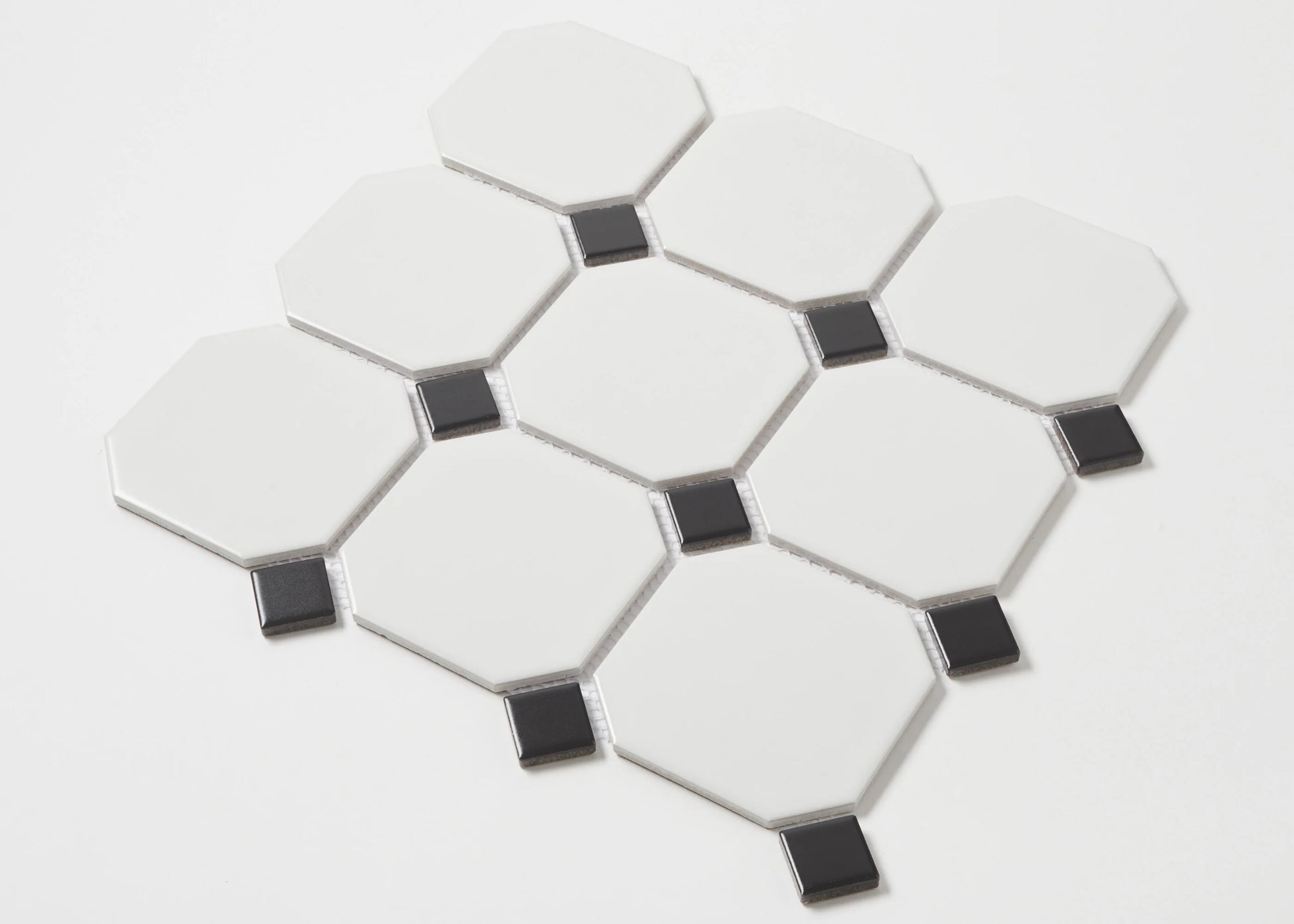 Pack shot of White and Black Matte Porcelain Glazed Octagon Large tiles showing matte white octagonal pieces with small black square dot inserts arranged in a classic pattern.