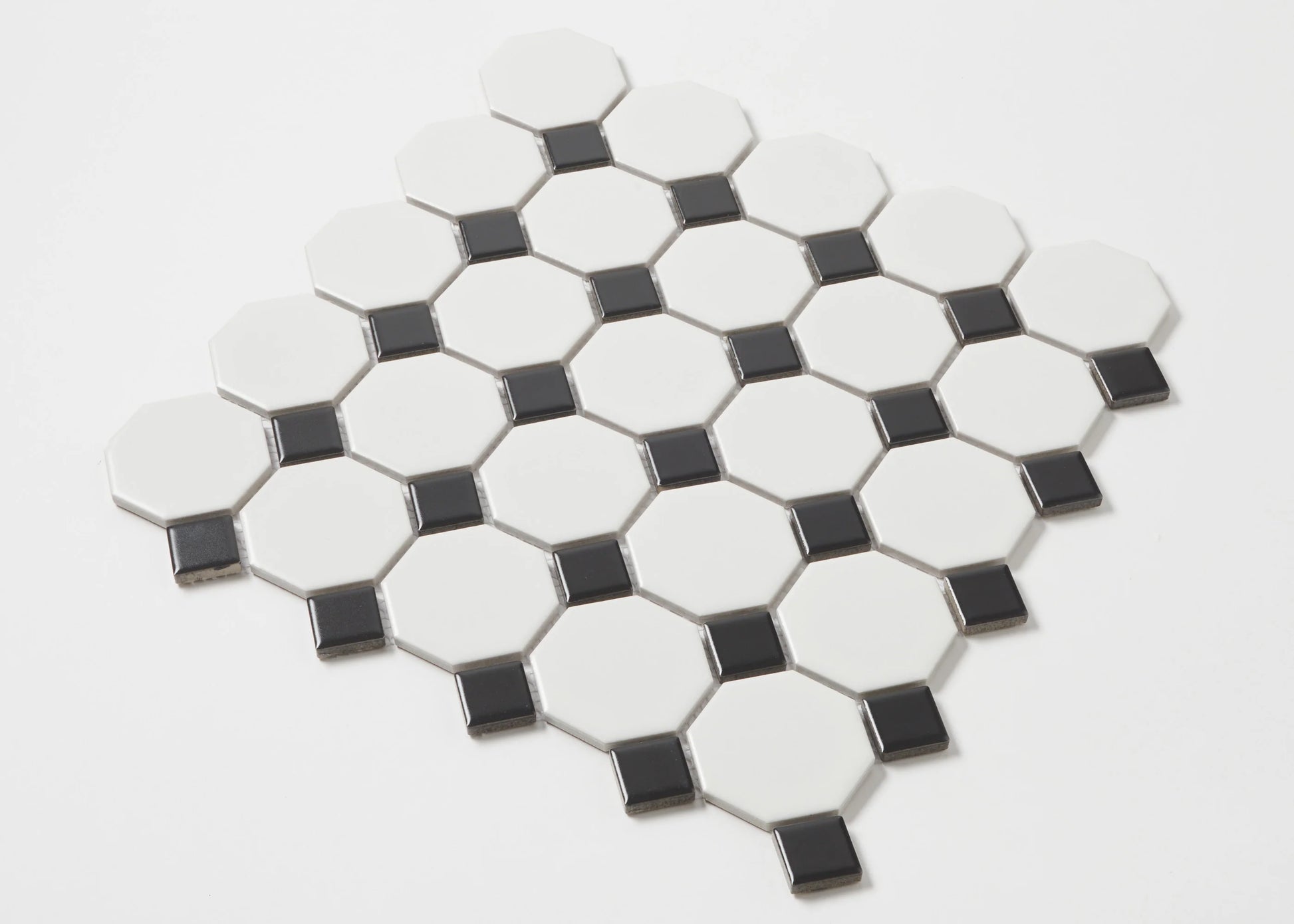 Pack shot of White and Black Matte Porcelain Glazed Octagon Small tiles showing glossy white octagon shapes with contrasting small black square dot inserts arranged in a diamond mosaic sheet.
