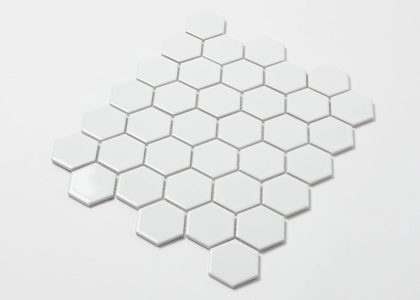 Pack shot of White Gloss Porcelain Glazed Hexagon 51x59mm tiles arranged in a honeycomb diamond pattern showing glossy white finish and grout spacing.