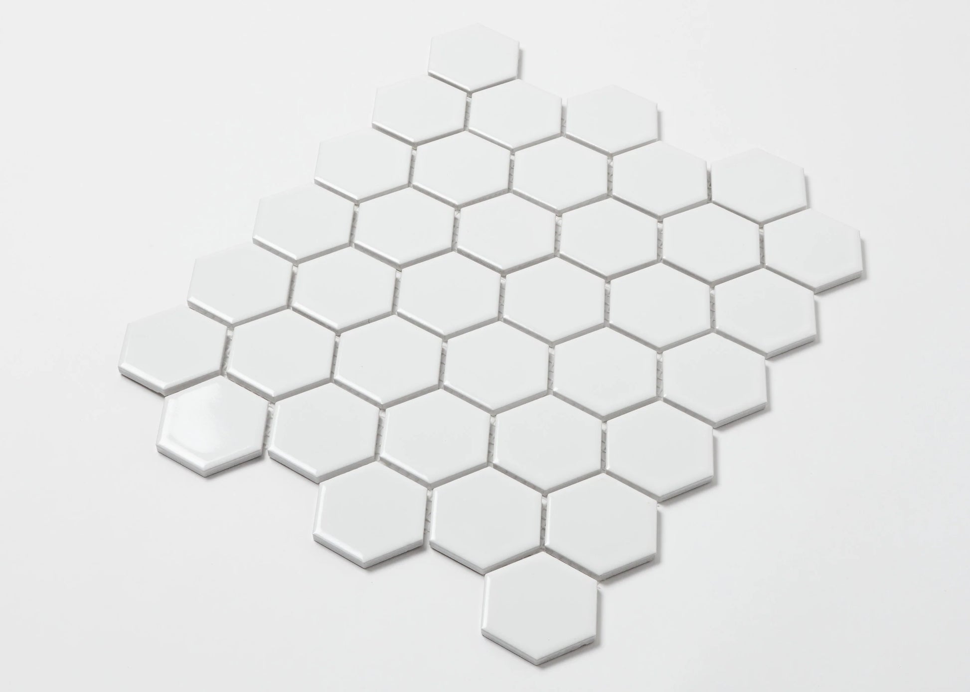 Pack shot of White Gloss Porcelain Glazed Hexagon 51x59mm tiles arranged in a honeycomb diamond pattern showing glossy white finish and grout spacing.