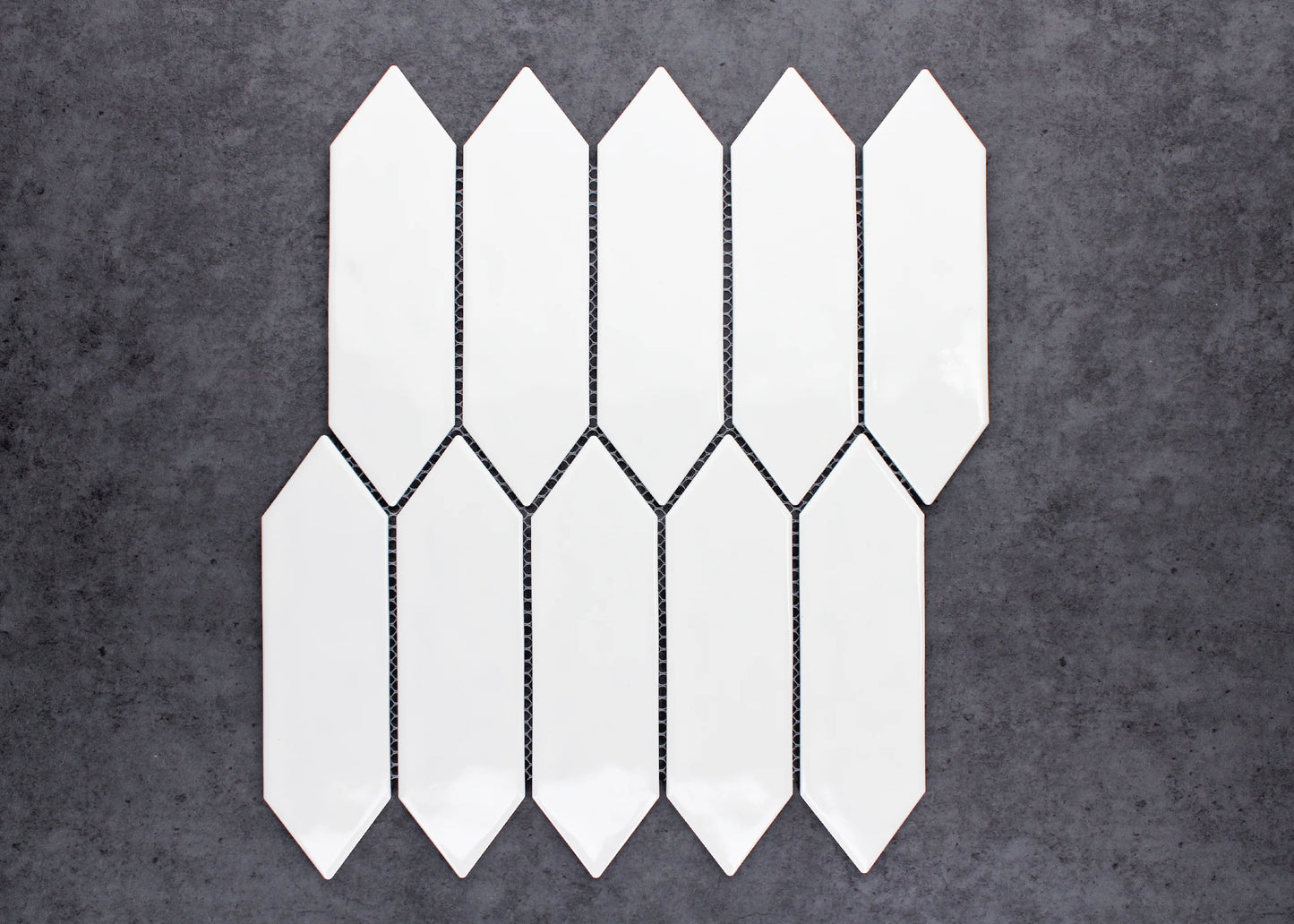 White Gloss Porcelain Glazed Ripple Surface Arrow 55x195mm tiles arranged in an interlocking staggered pattern showing glossy white elongated arrow-shaped ceramic pieces against a dark grey background.