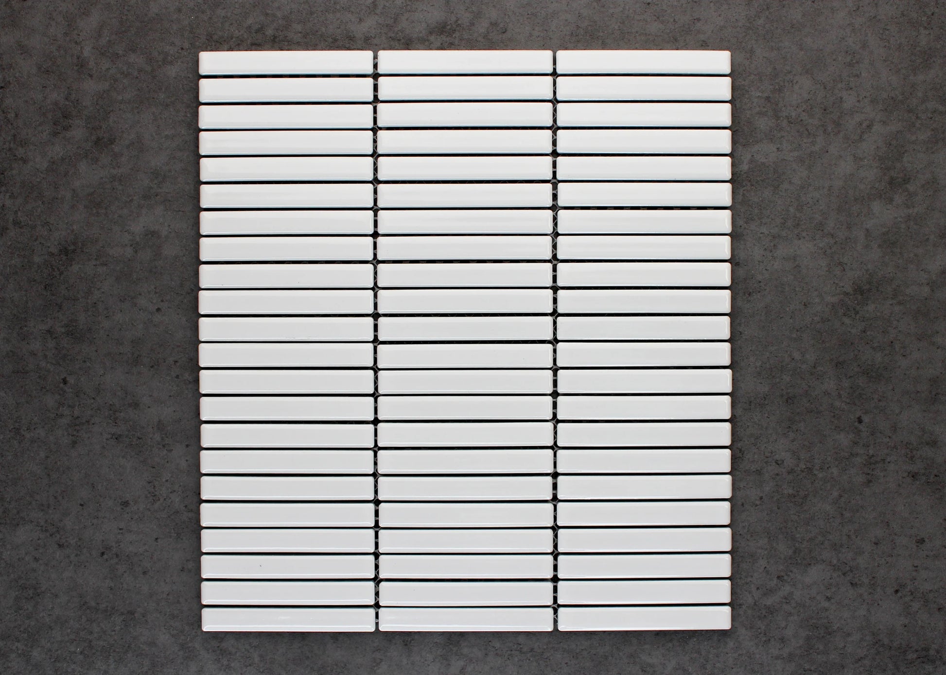 Flat lay of White Gloss Porcelain KitKat 12x92mm tiles arranged in three stacked columns showing glossy white finish and slim rectangular format.
