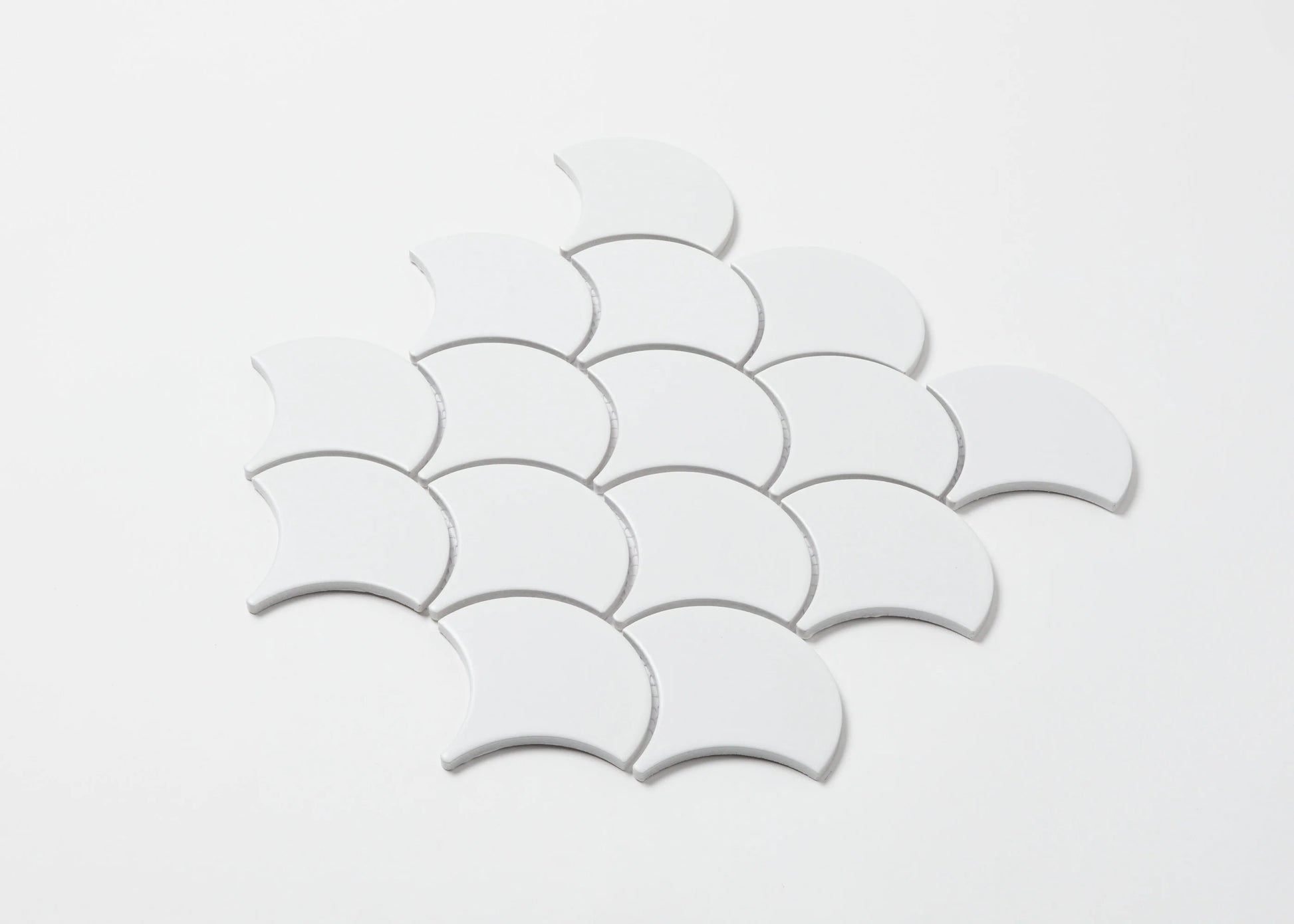 Pack shot of White Matt Porcelain Glazed Fishscale 95x87mm tiles arranged in an overlapping scallop pattern against a white background.