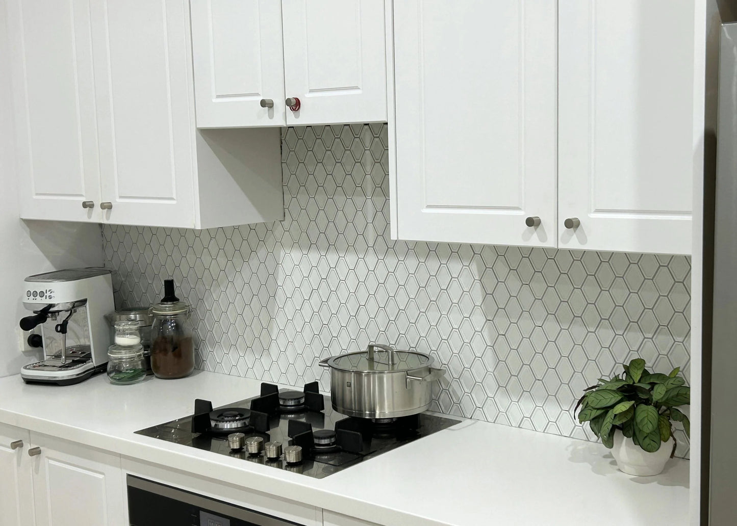 White Matte Internal Porcelain Glazed Honeycombe Internal 46.5x60mm installed as a kitchen splashback behind a gas cooktop with white shaker cabinetry.