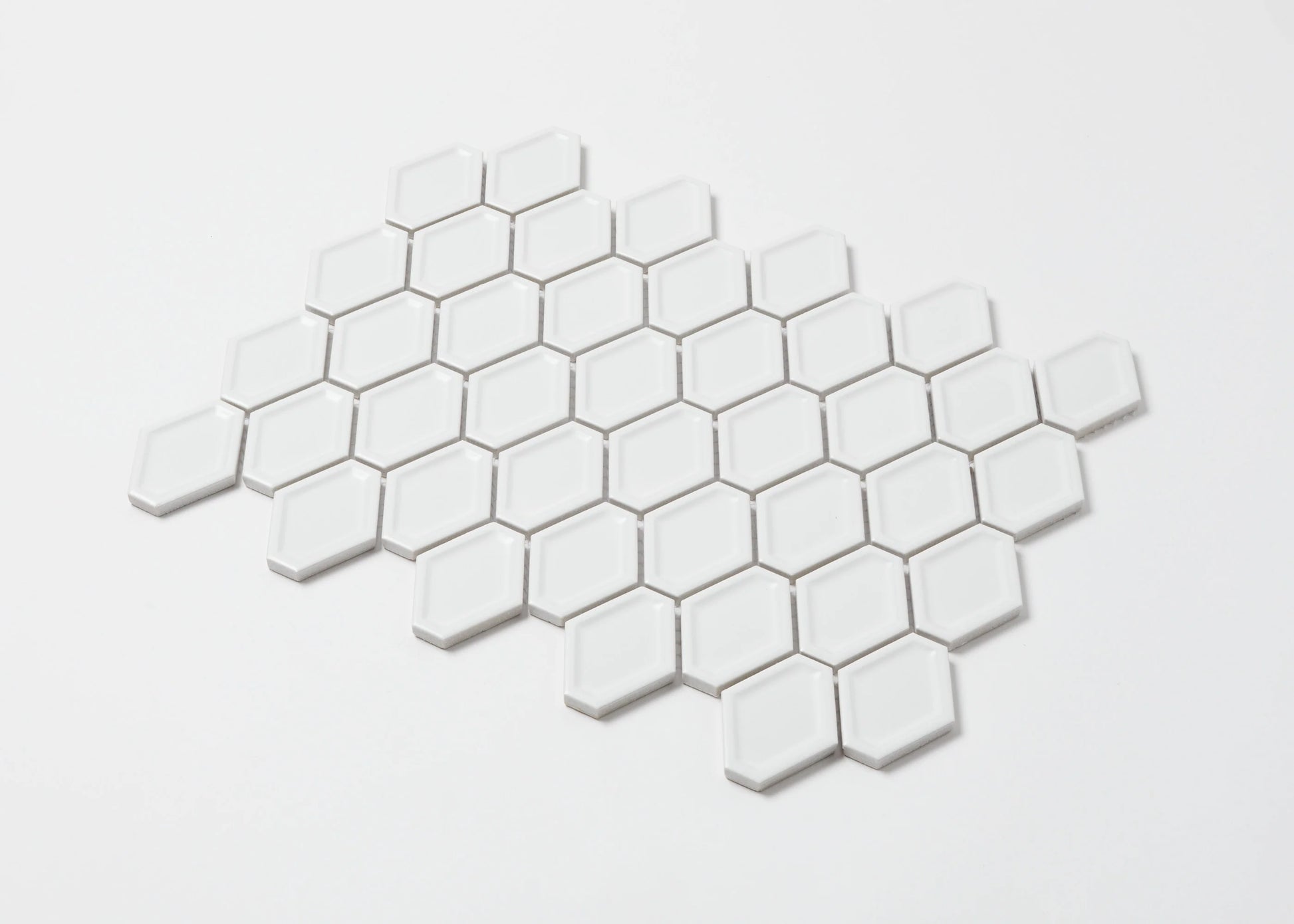Pack shot of White Matte Internal Porcelain Glazed Honeycombe Internal 46.5x60mm tiles arranged in a honeycomb mosaic pattern showing glossy white elongated hexagonal shapes.