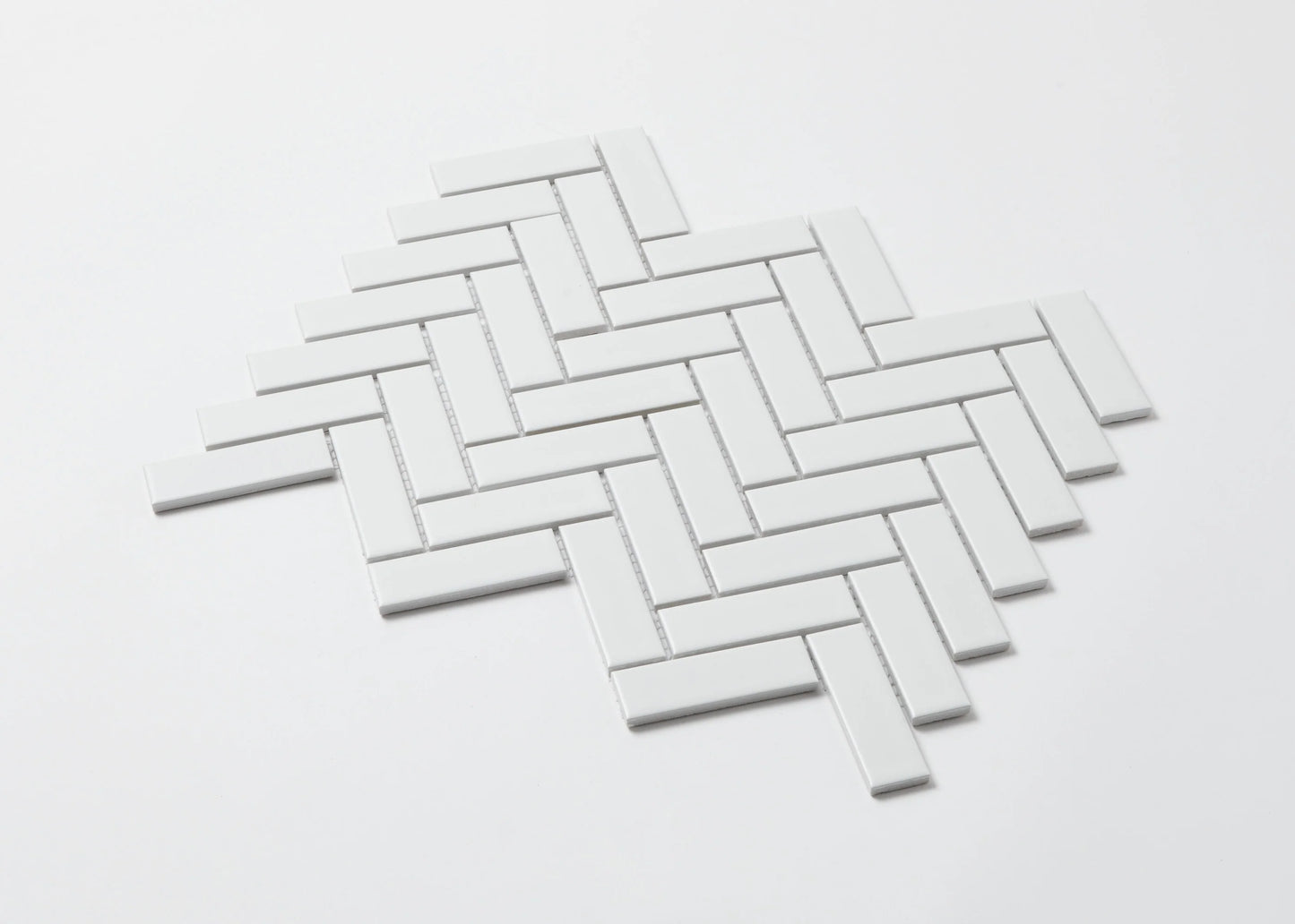 Pack shot of White Matte Porcelain Glazed Herringbone Bond 23x73mm tiles arranged in a classic diagonal herringbone pattern with a clean white matte finish.
