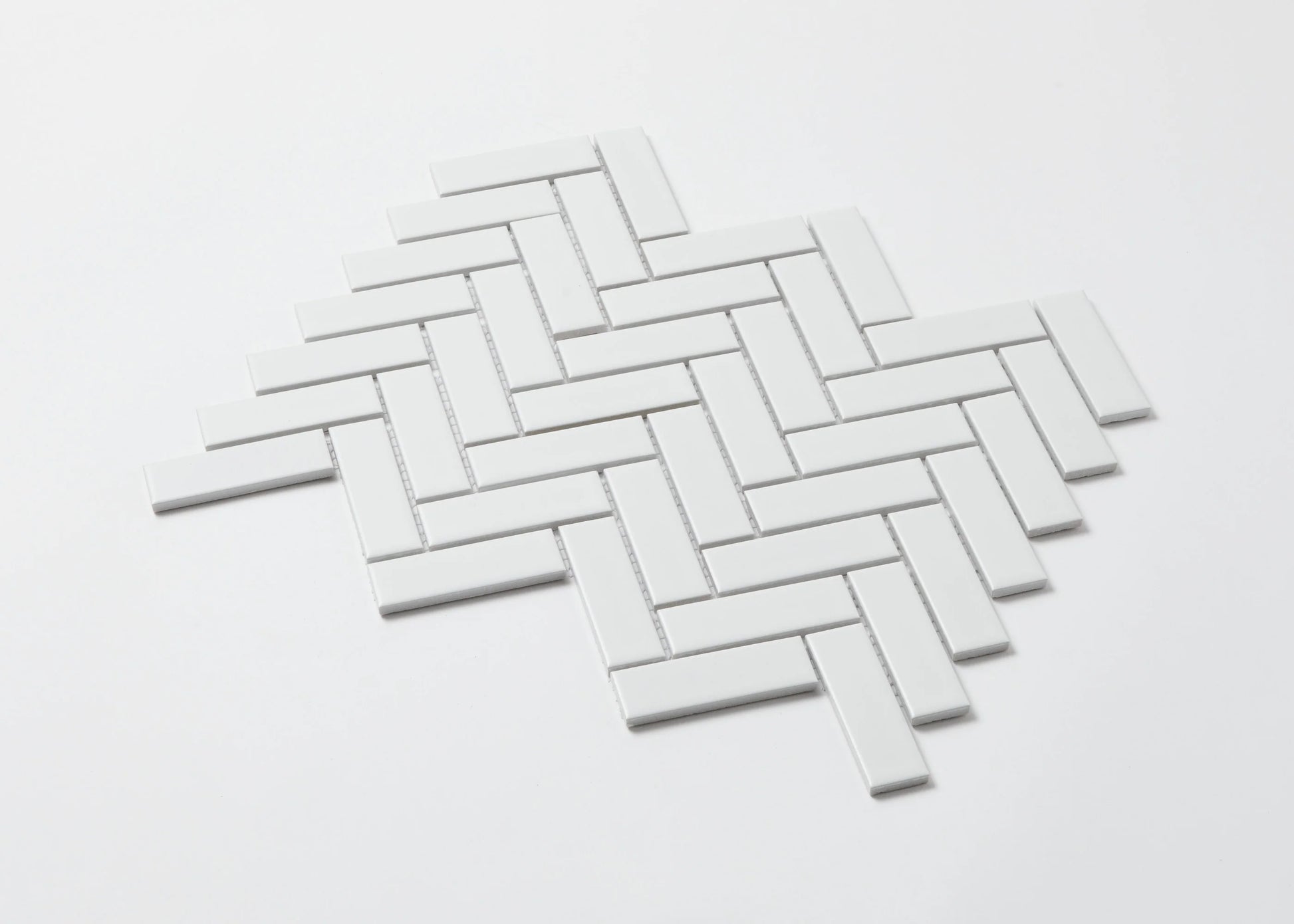 Pack shot of White Matte Porcelain Glazed Herringbone Bond 23x73mm tiles arranged in a classic diagonal herringbone pattern with a clean white matte finish.