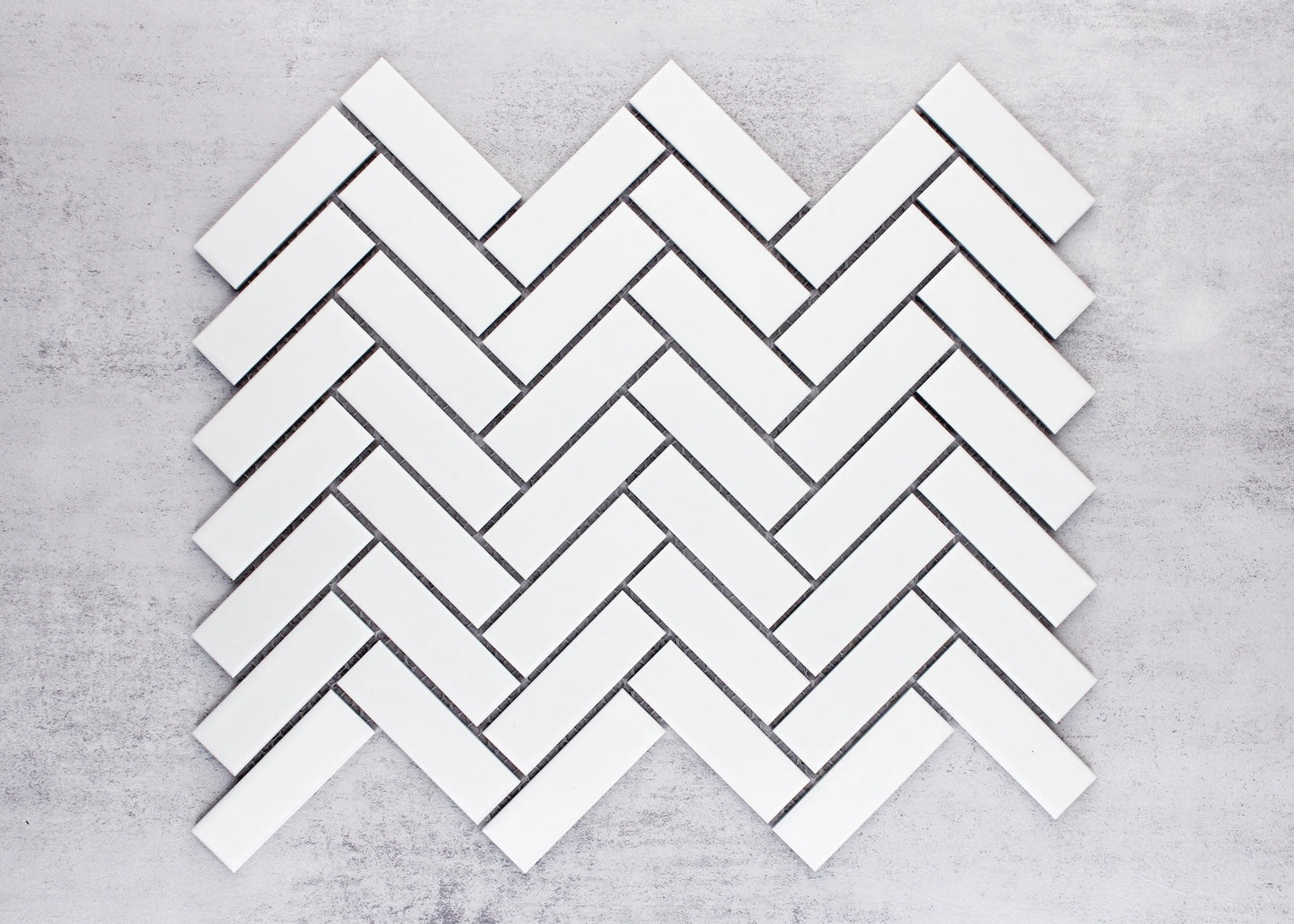White Matte Porcelain Glazed Herringbone Bond 23x73mm tiles arranged in a classic herringbone pattern layout showing the matte white finish and angled brick formation.