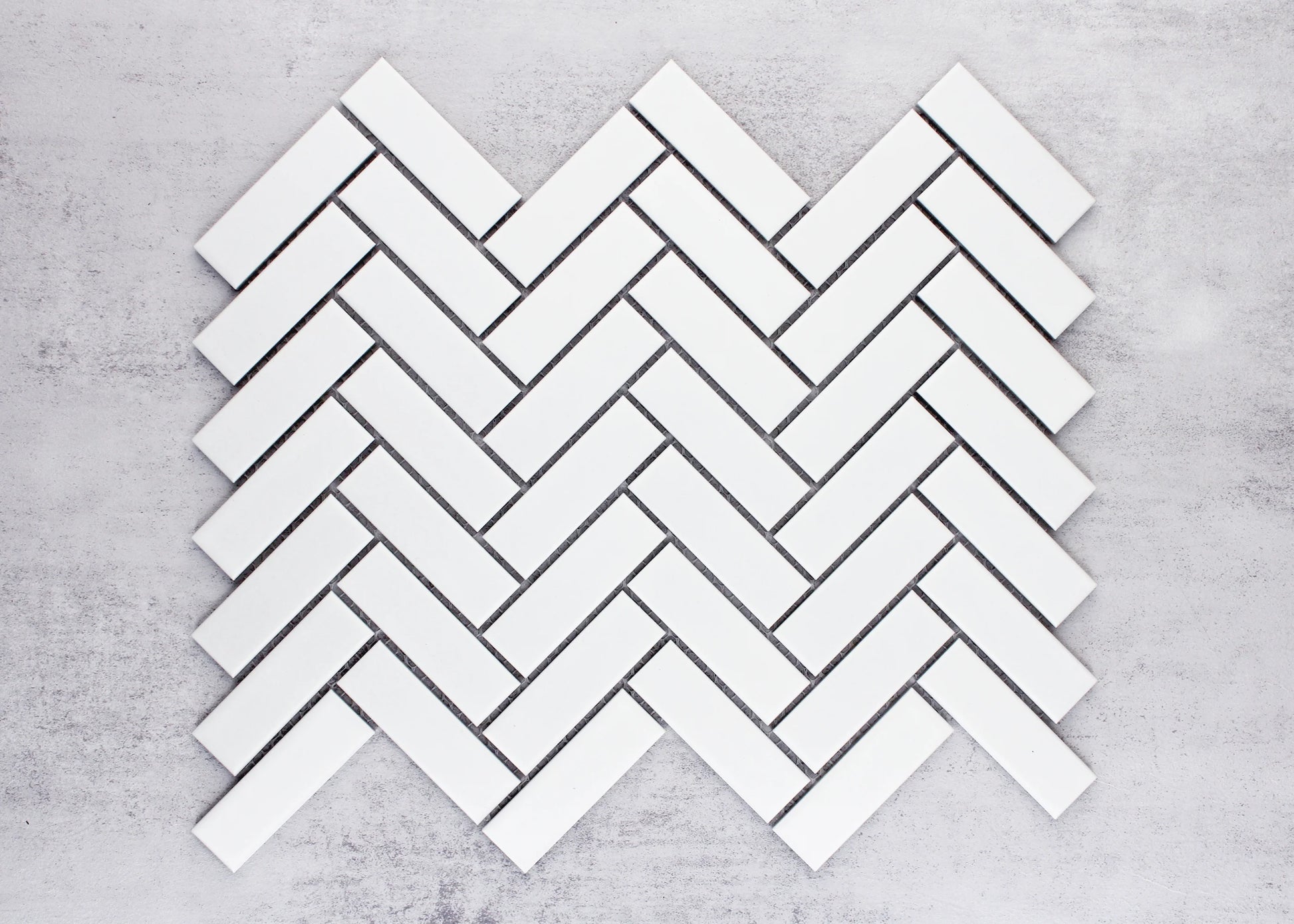 White Matte Porcelain Glazed Herringbone Bond 23x73mm tiles arranged in a classic herringbone pattern layout showing the matte white finish and angled brick formation.
