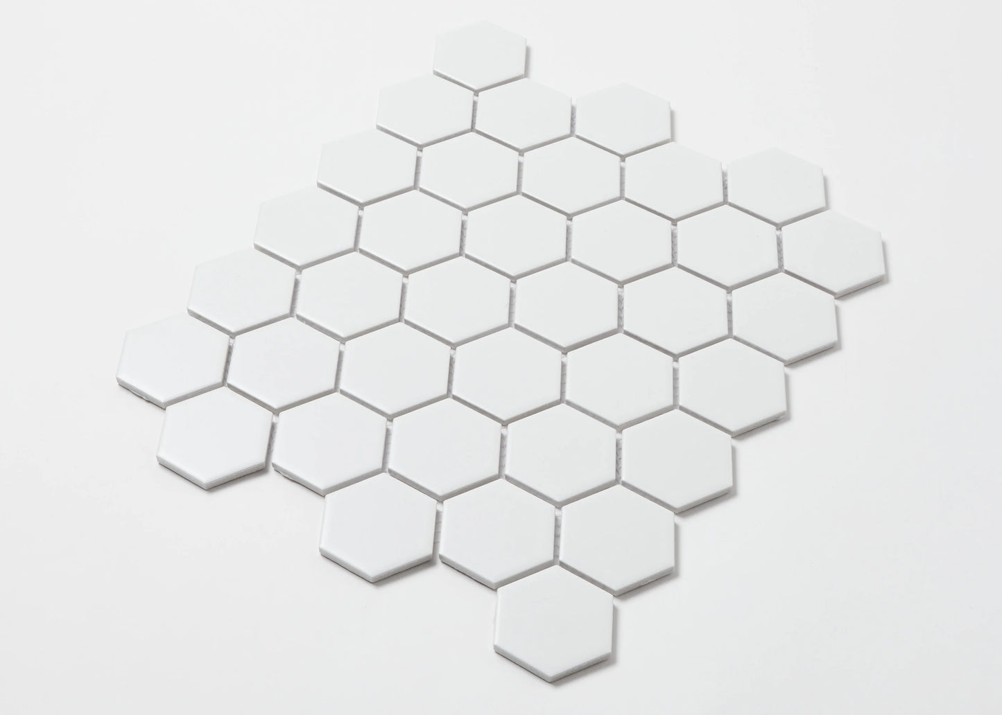 Pack shot of White Matte Porcelain Glazed Hexagon 51x59mm tiles arranged in a honeycomb mosaic pattern against a white background.