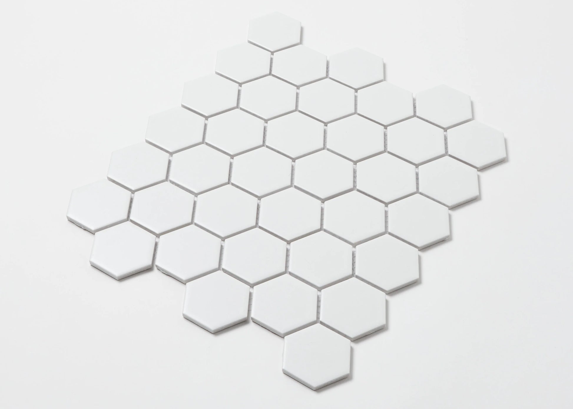 Pack shot of White Matte Porcelain Glazed Hexagon 51x59mm tiles arranged in a honeycomb mosaic pattern against a white background.