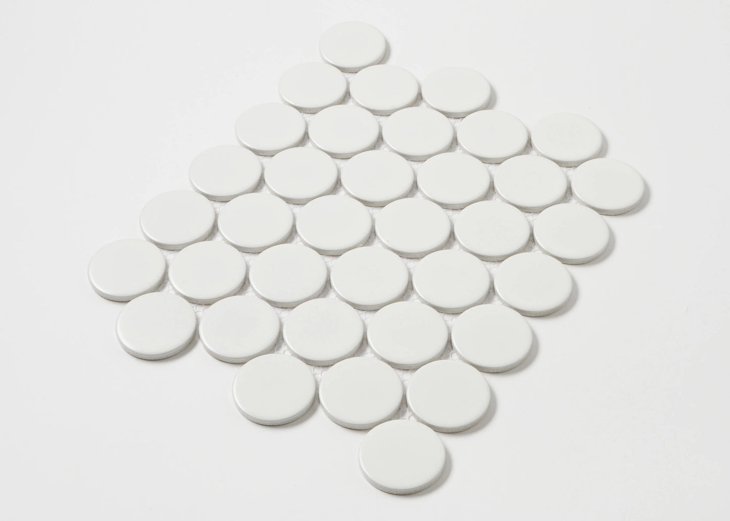 Overhead pack shot of White Matte Porcelain Glazed Penny Round 48mm tiles arranged in a diamond grid pattern showing matte white finish and circular shape.