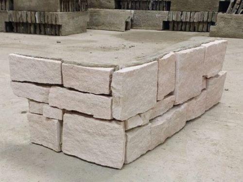 White Sandstone Z Panel Interlock 200x600mm shown as a dry-stacked corner display with rough-textured pale beige stone blocks in an interlocking arrangement.