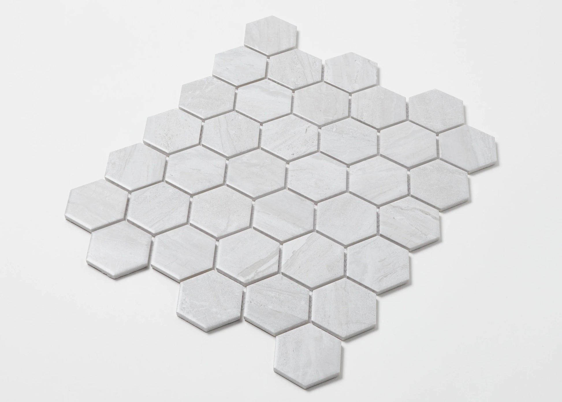 Pack shot of Wooden Grey Matte Porcelain Glazed Hexagon 51x59mm tiles arranged in a diamond mosaic sheet pattern showing subtle grey veining and matte finish.