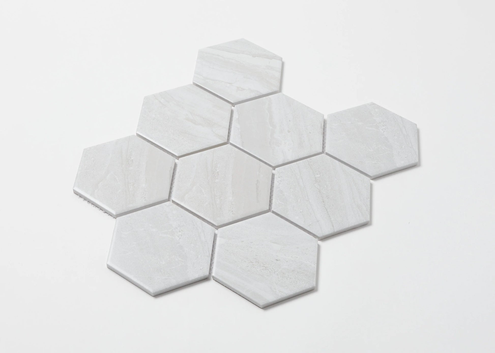 Pack shot of Wooden Grey Matte Porcelain Glazed Hexagon 95x110mm tiles arranged in a honeycomb cluster, showing subtle grey veining and matte finish on a white background.