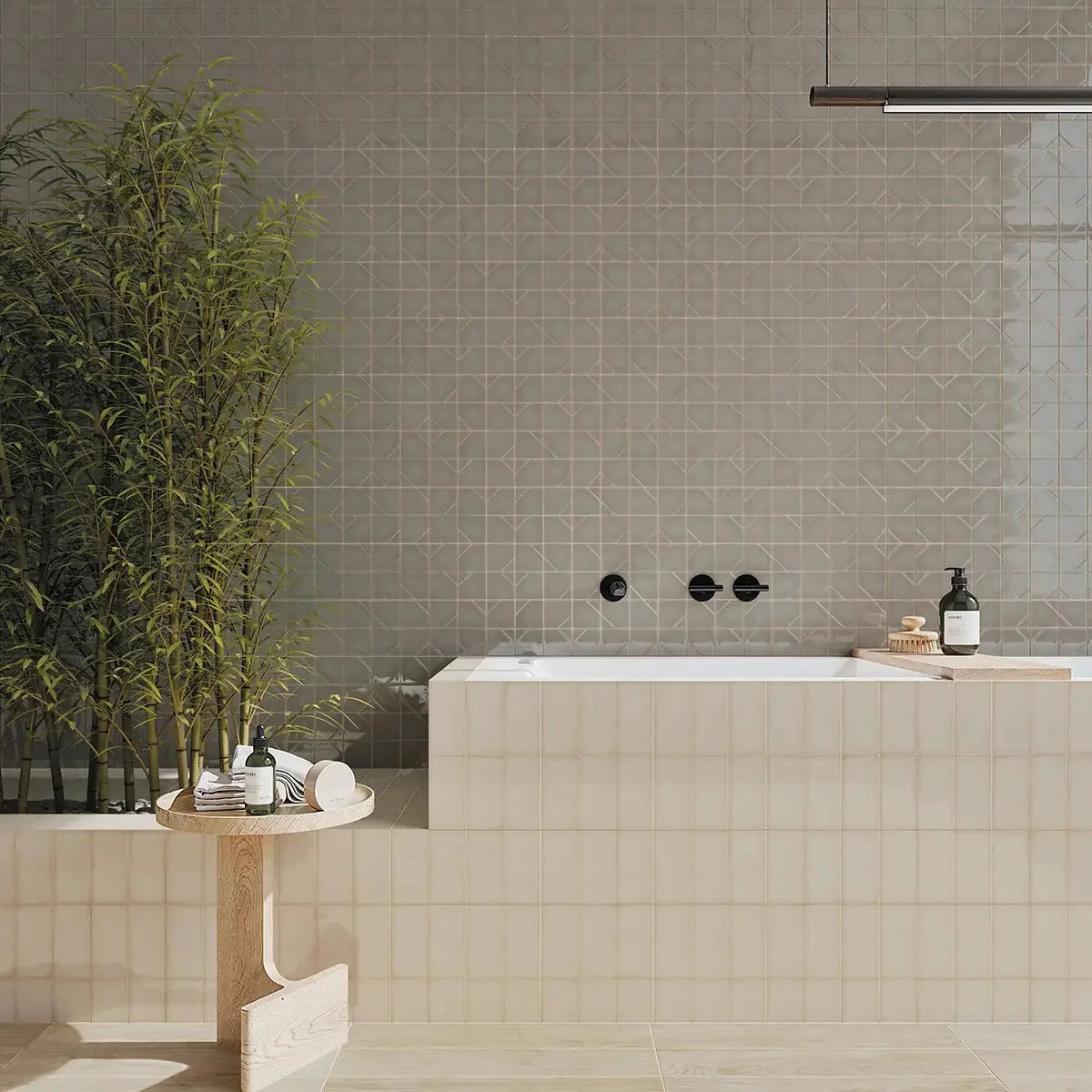 Yoko Origami Pewter Gloss 62.5x125mm tiles installed as a full bathroom feature wall behind a freestanding bath with black wall-mounted faucets and bamboo plant.