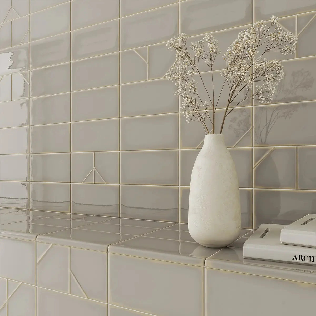 Yoko Origami Pewter Gloss 62.5x125mm tiles installed on a wall and tiled shelf styled with a white ceramic vase of dried gypsophila and architecture books.
