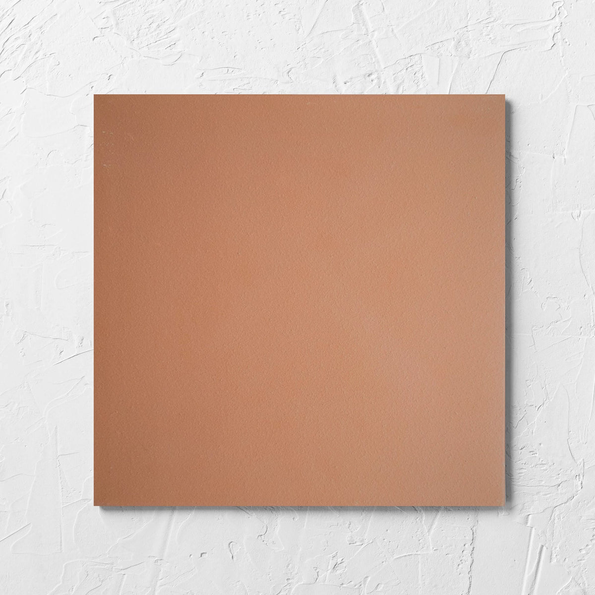 Yulara Terracotta 300x300mm tile laid flat on a white rendered wall, showing the tile surface